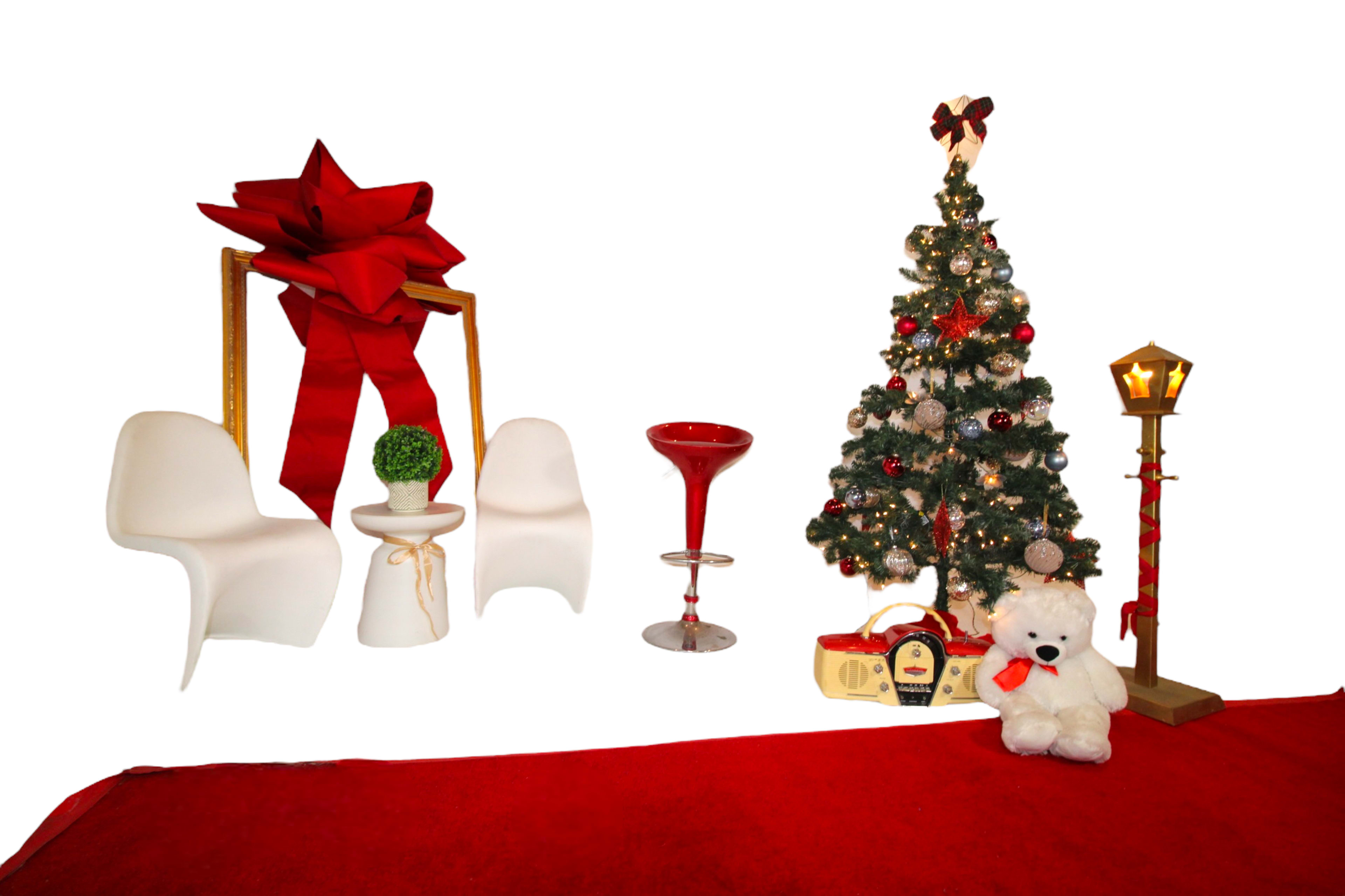 The scene features a decorated Christmas tree, a red carpet, two white chairs with a large red bow, and festive decorations including a teddy bear and a lamp.