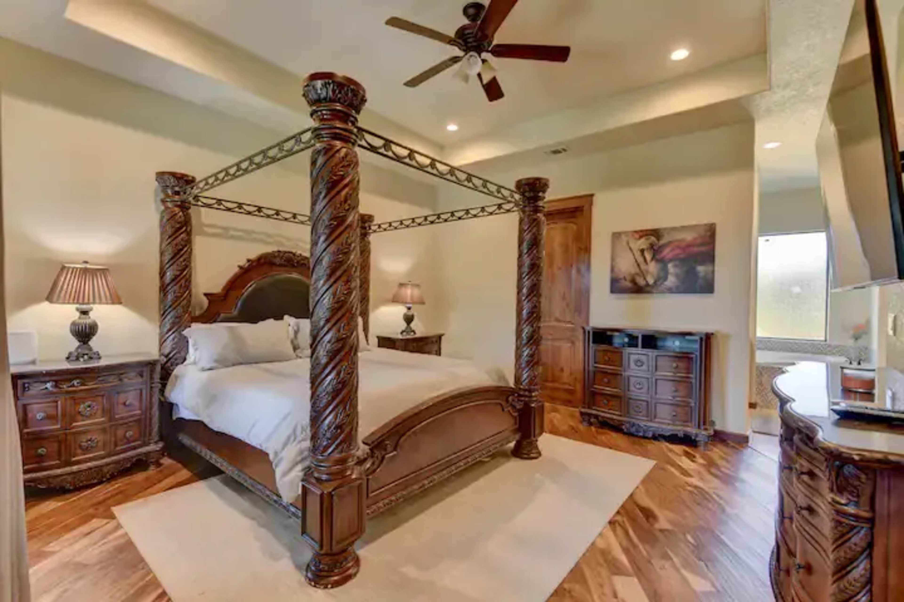 A bedroom featuring a four-poster bed with ornate wooden columns, two bedside lamps, and matching furniture.