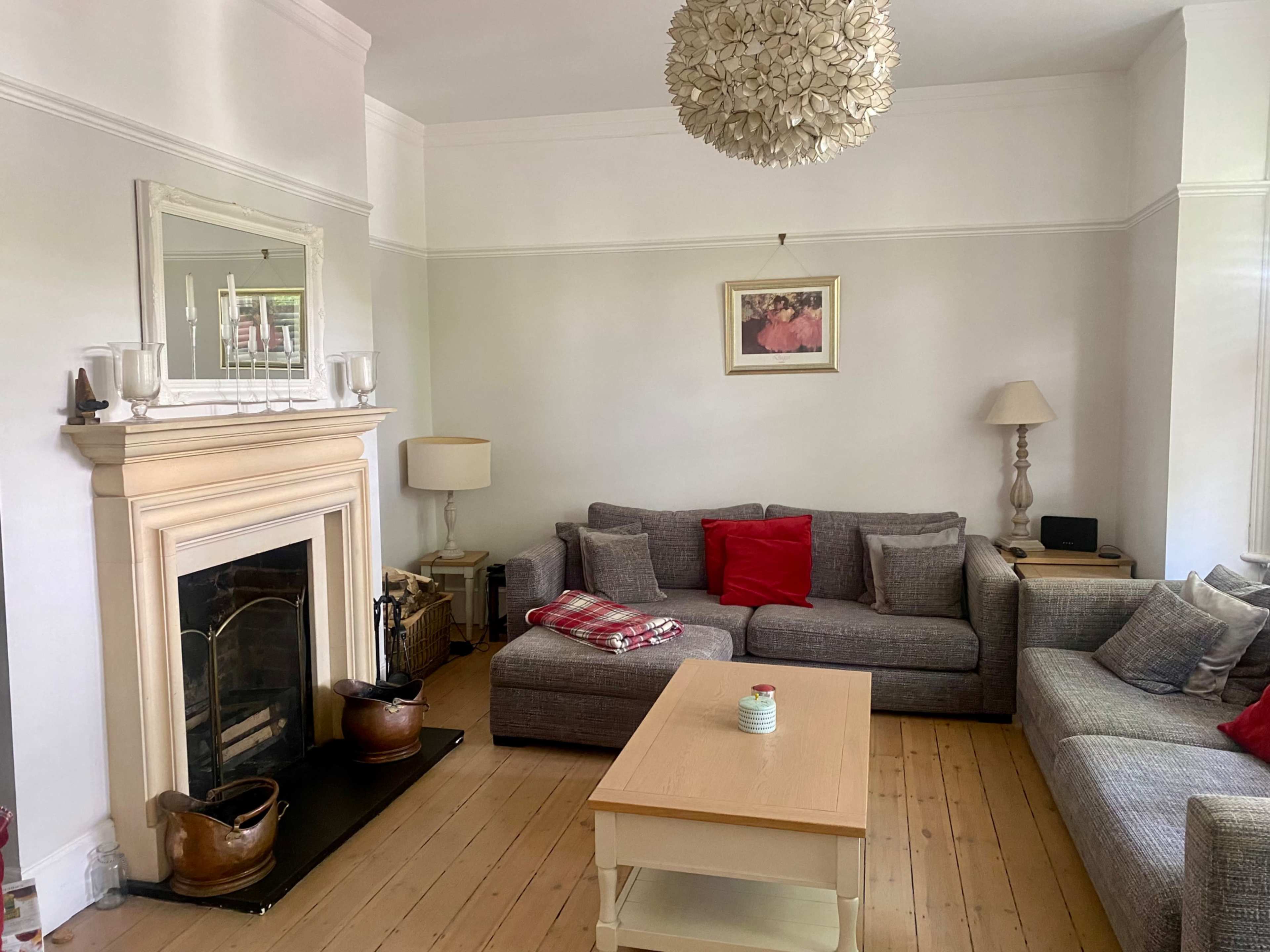 The living room features a light-colored couch arrangement, a central wooden coffee table, and a decorative fireplace with a mirror above it.