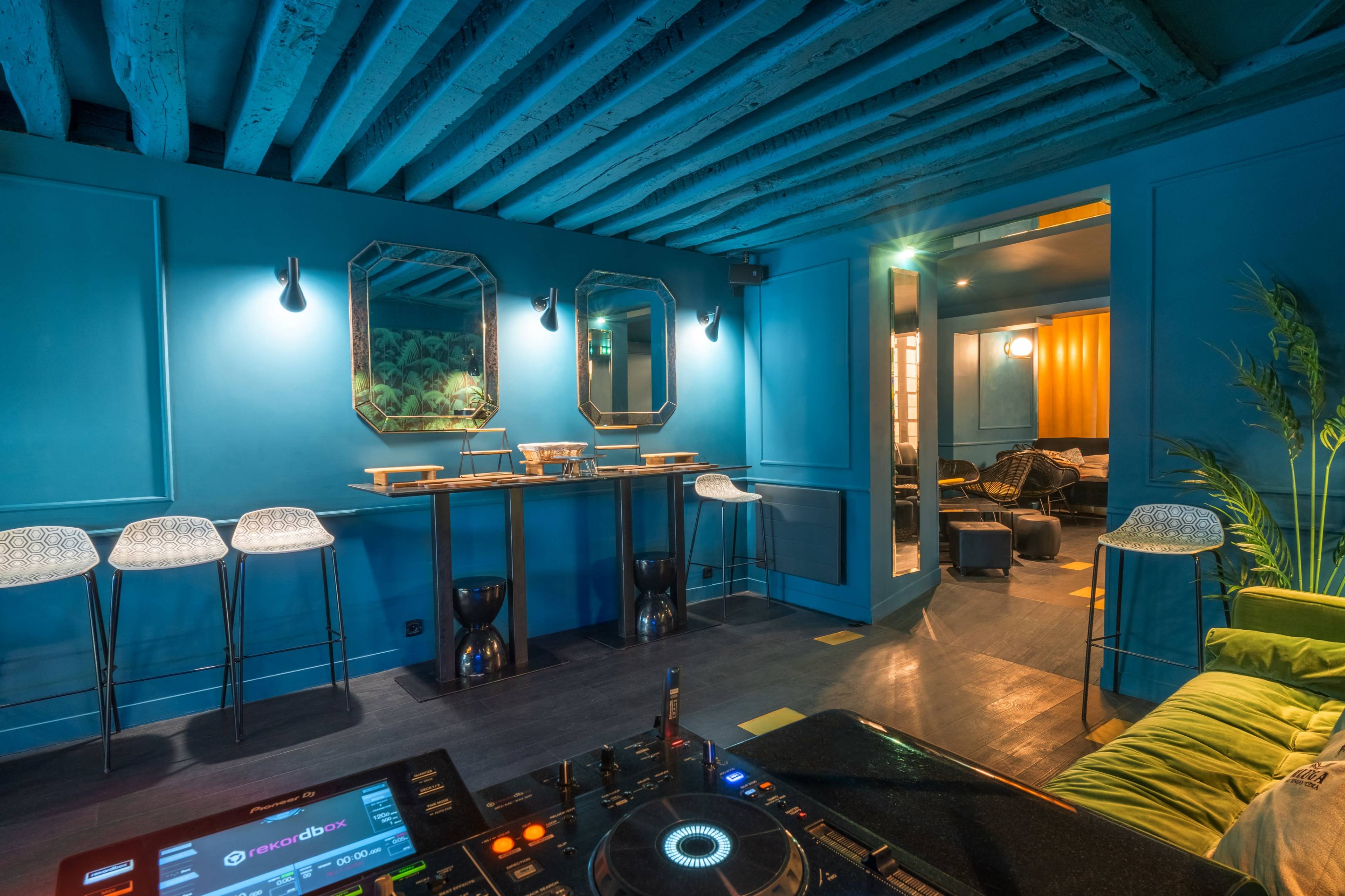 A blue-walled room with modern bar stools, mirrors, and a DJ turntable in the foreground.