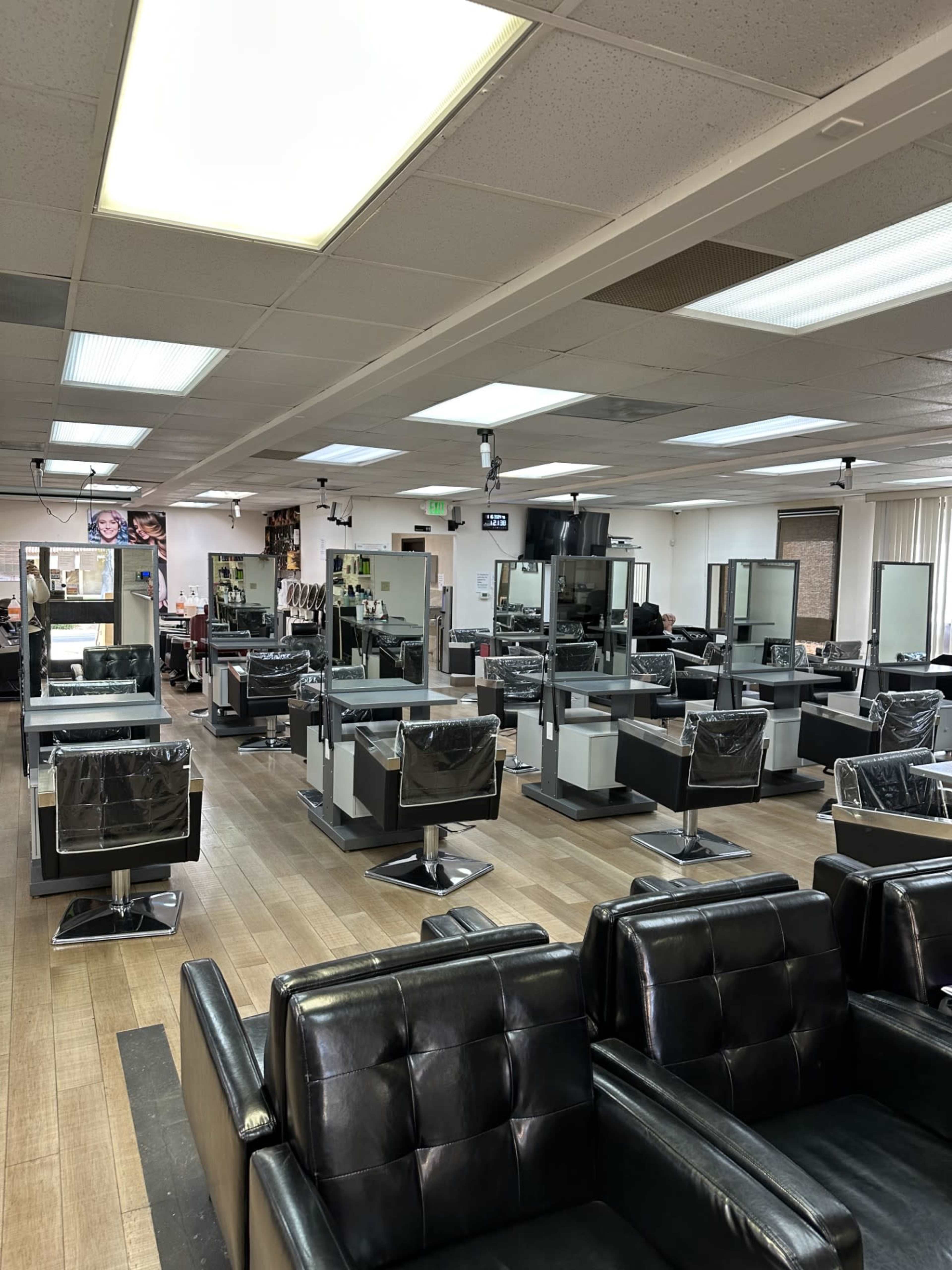 A spacious hair salon featuring several styling stations and black chairs arranged in a tidy layout.