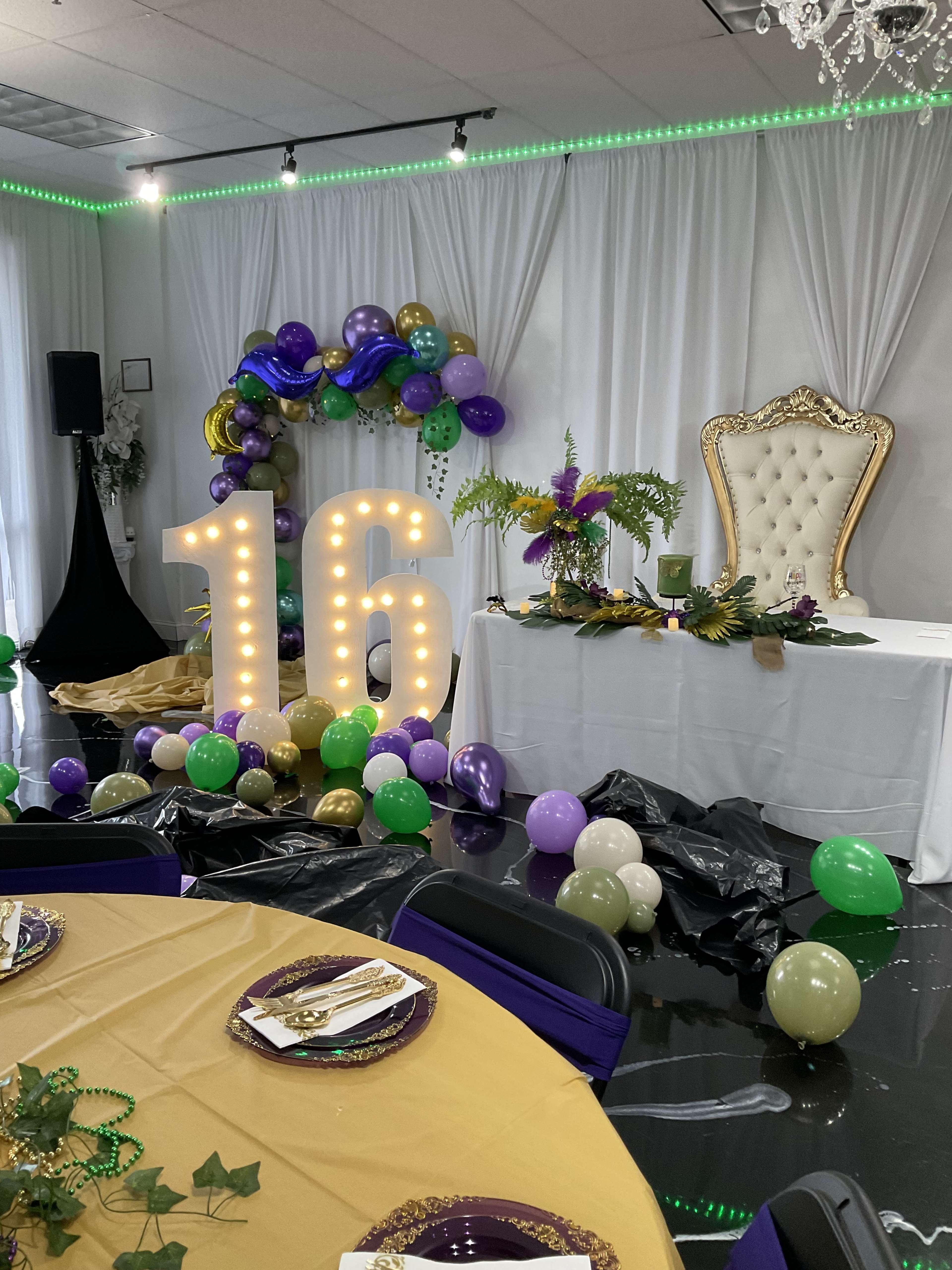 The image shows a festive 16th birthday party setup with large illuminated "16" numbers, a decorated table, balloons, and a throne-like chair against a backdrop of draped fabric.