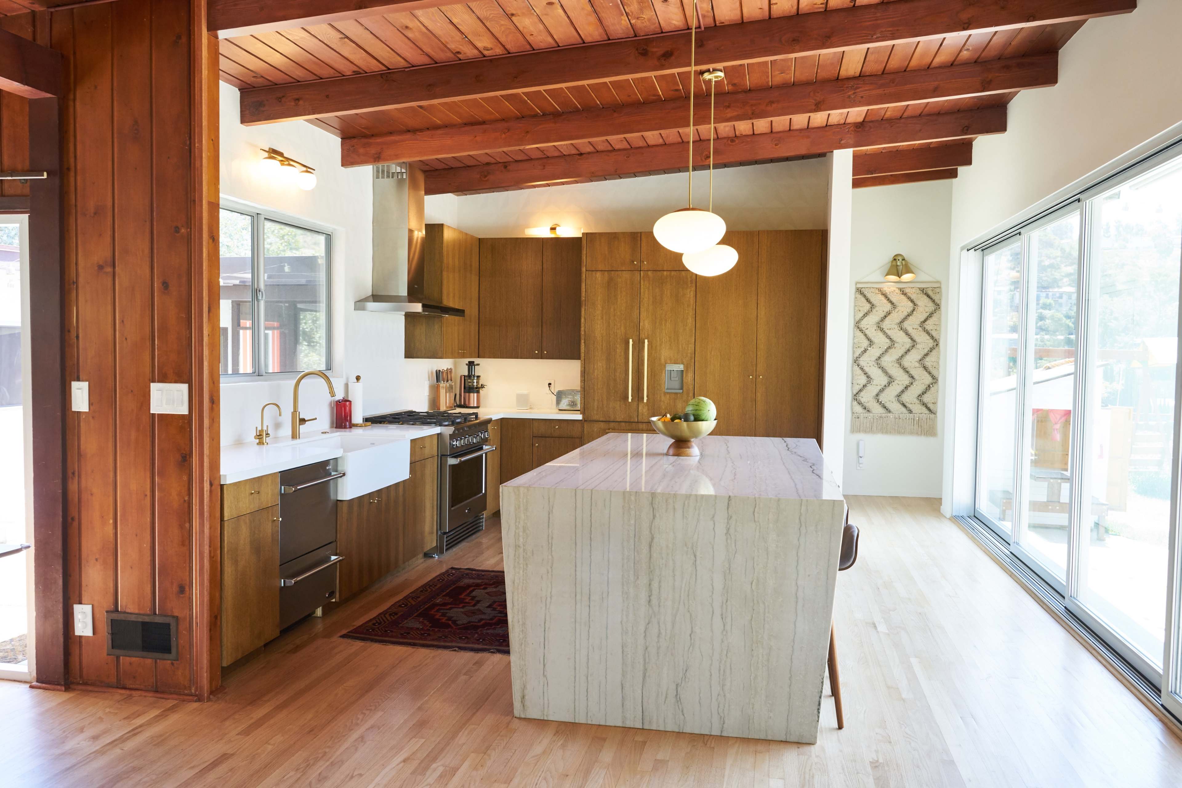 A modern kitchen with wooden beams, a marble-topped island, and contemporary appliances.