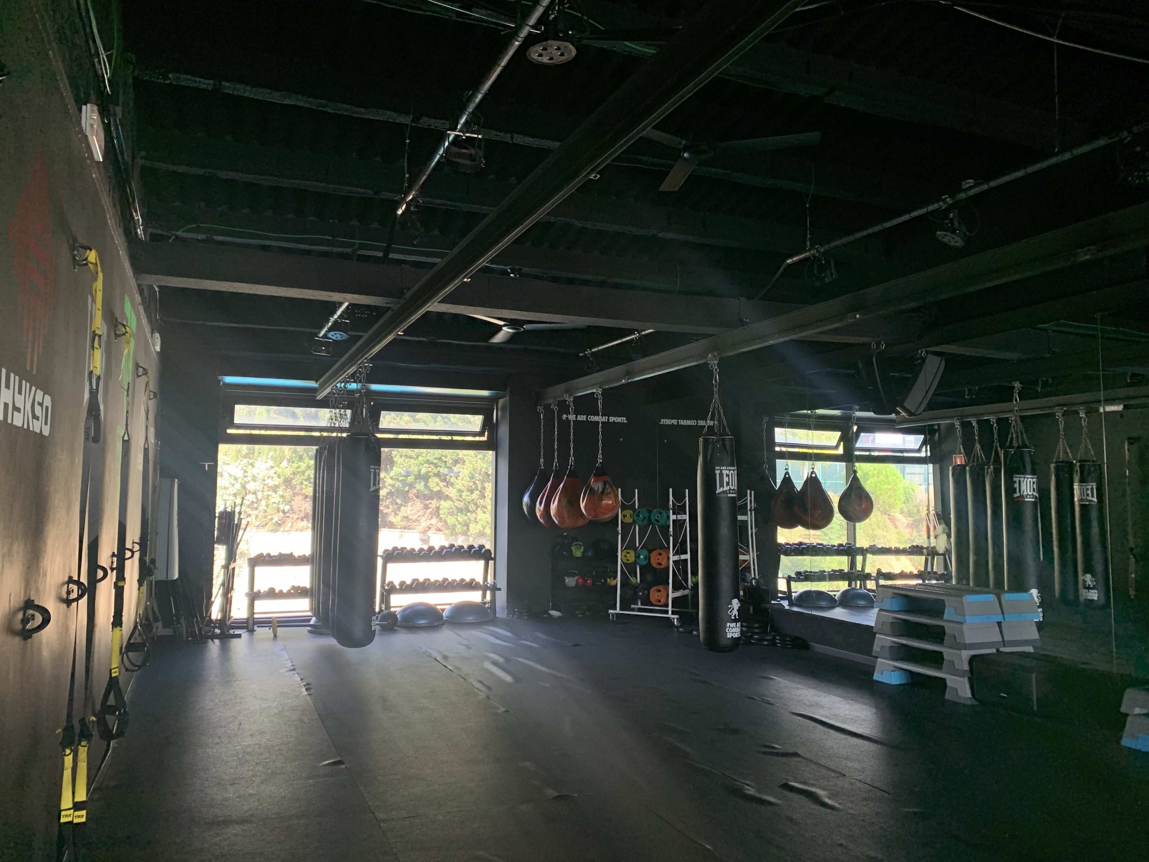 An empty gym space with hanging punching bags and various fitness equipment neatly arranged against the walls.