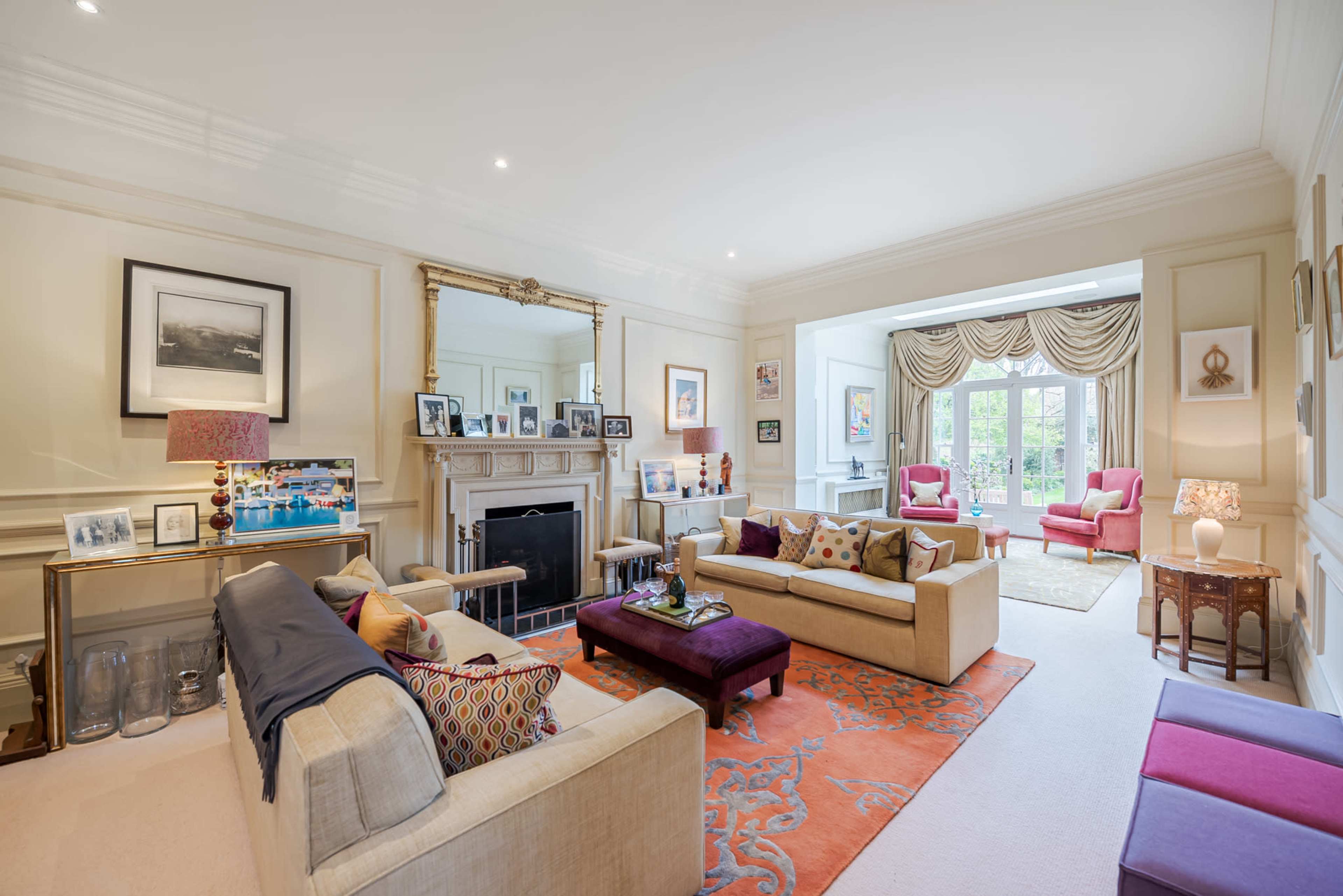 The living room features a symmetrical layout with two sofas facing each other, a central coffee table, and large windows that illuminate the space.