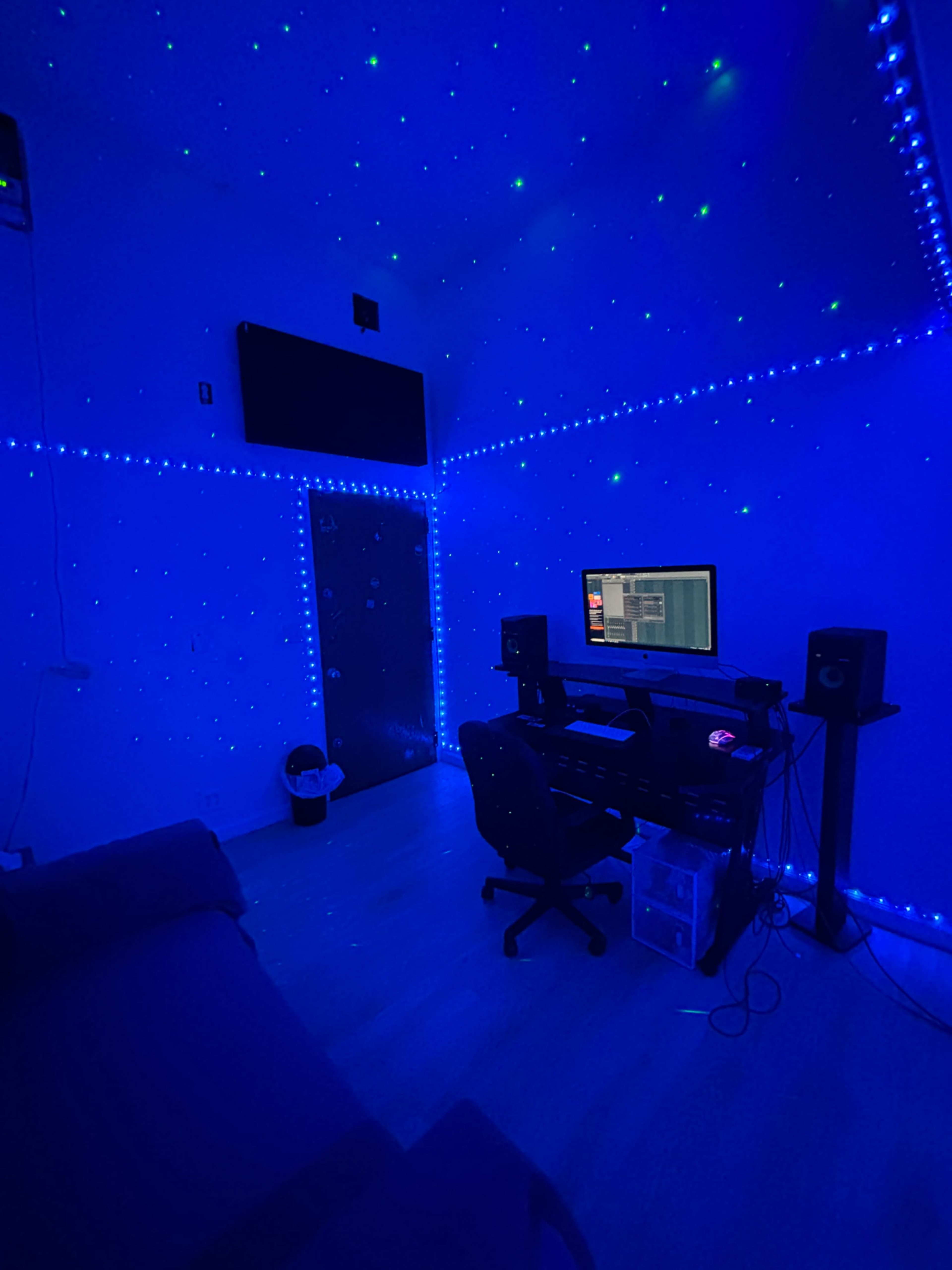 The room features blue LED lights creating a starry effect on the walls, with a desk, computer, and speakers arranged in the center.
