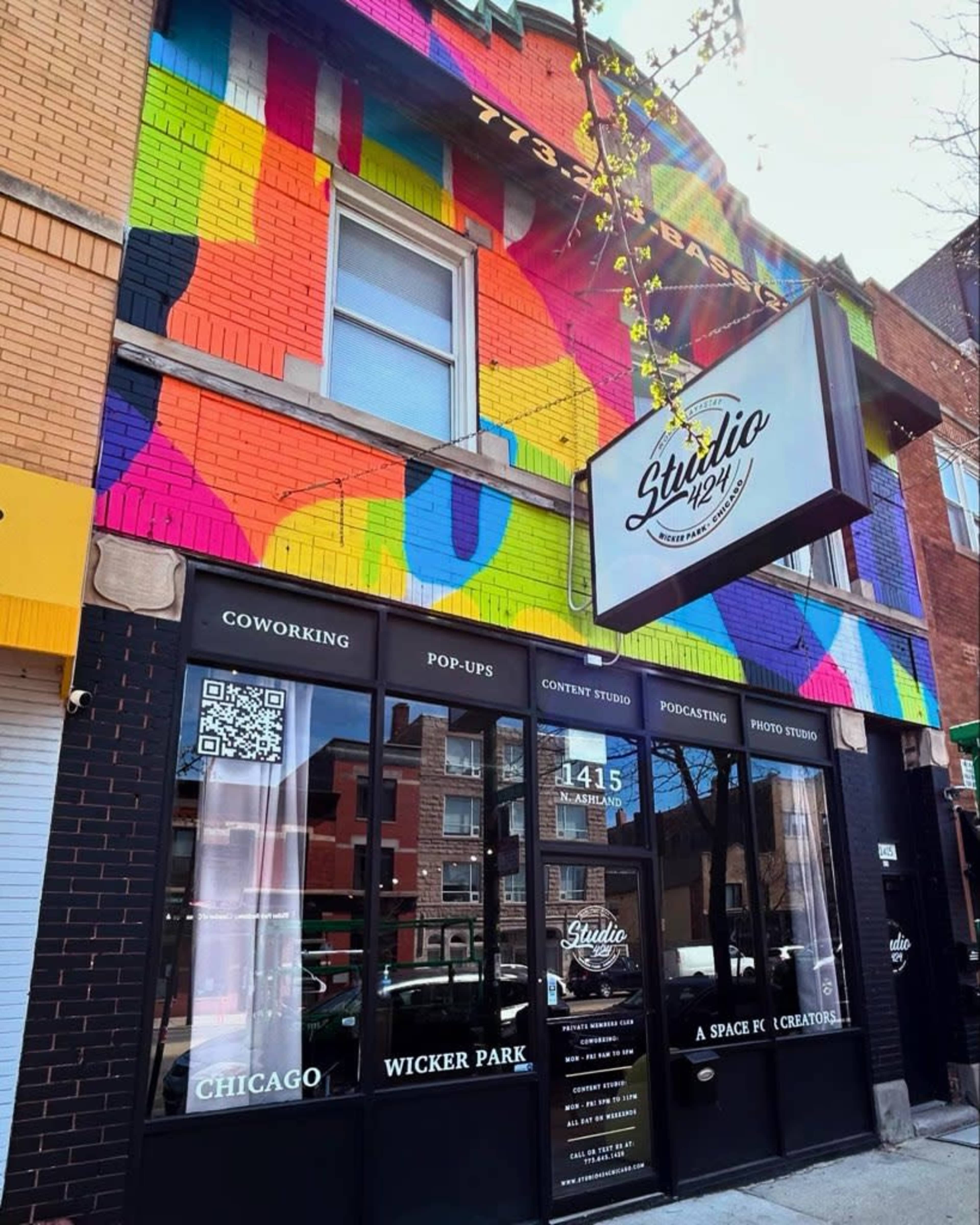The image shows a colorful mural on a building in Wicker Park, Chicago, with a storefront featuring signs for coworking, pop-ups, content studio, podcasting, and photo studio services.