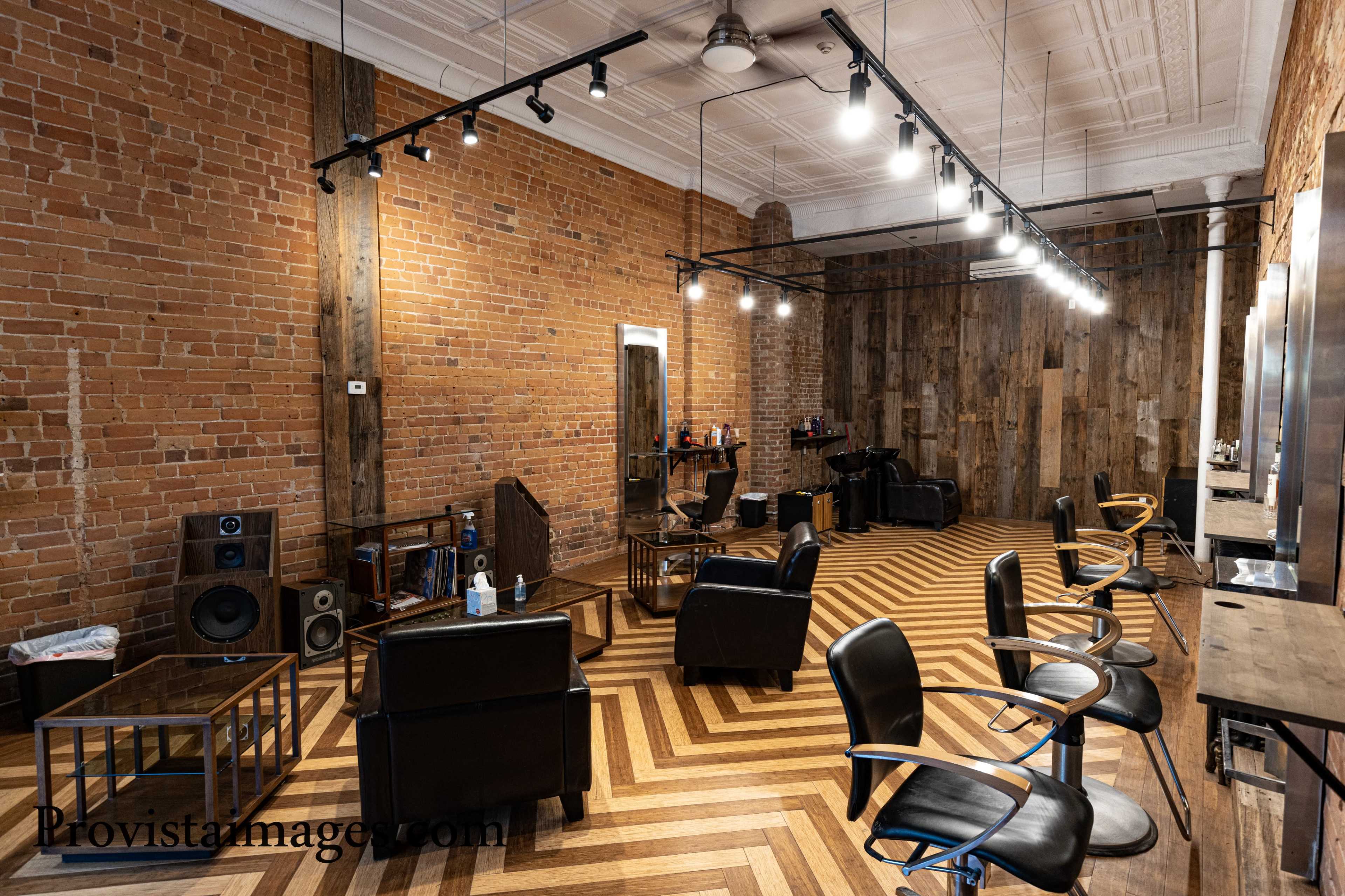 A modern hair salon with exposed brick walls, wooden accents, and a zigzag patterned floor.