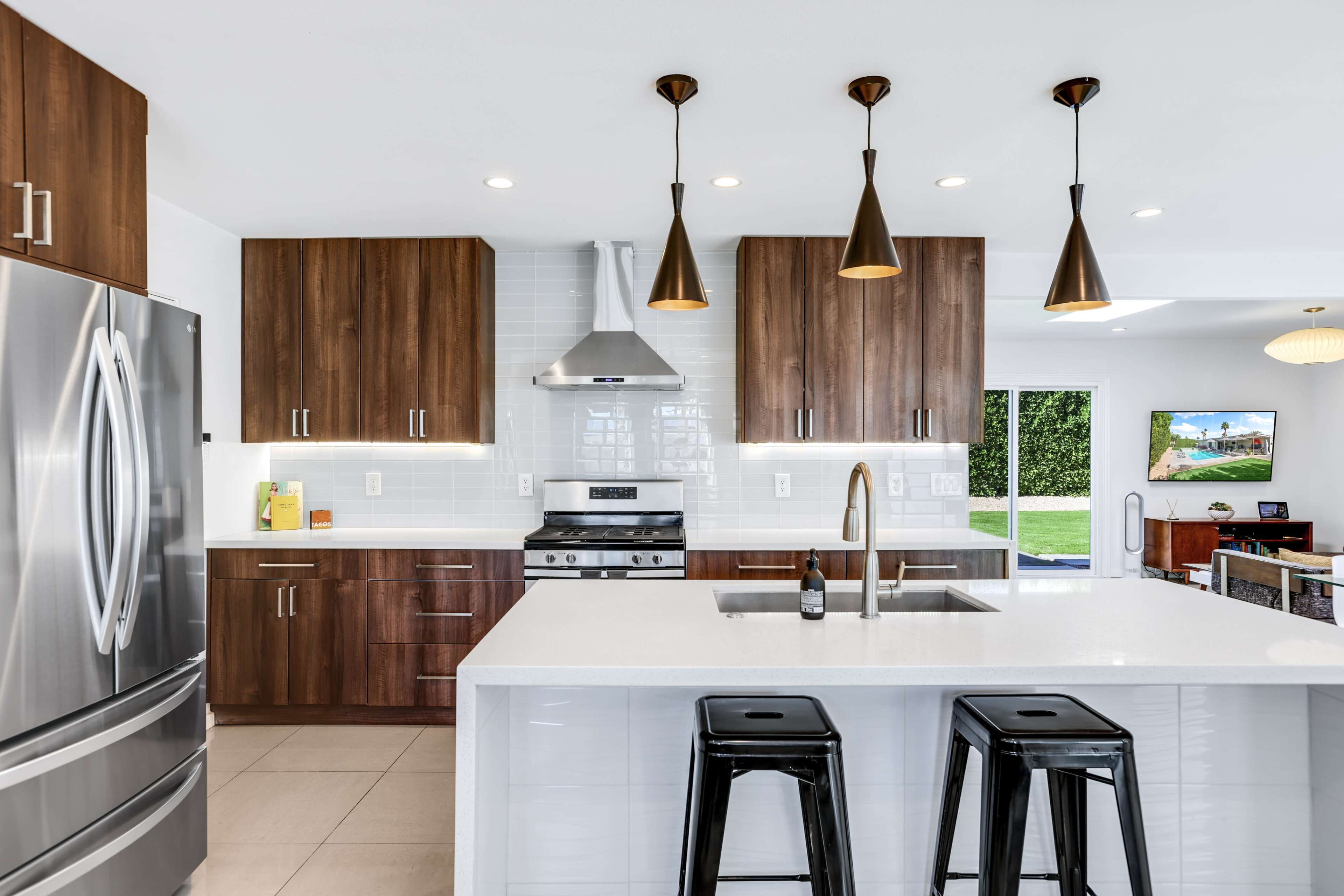 A modern kitchen with dark wood cabinets, stainless steel appliances, and a central island with black bar stools.
