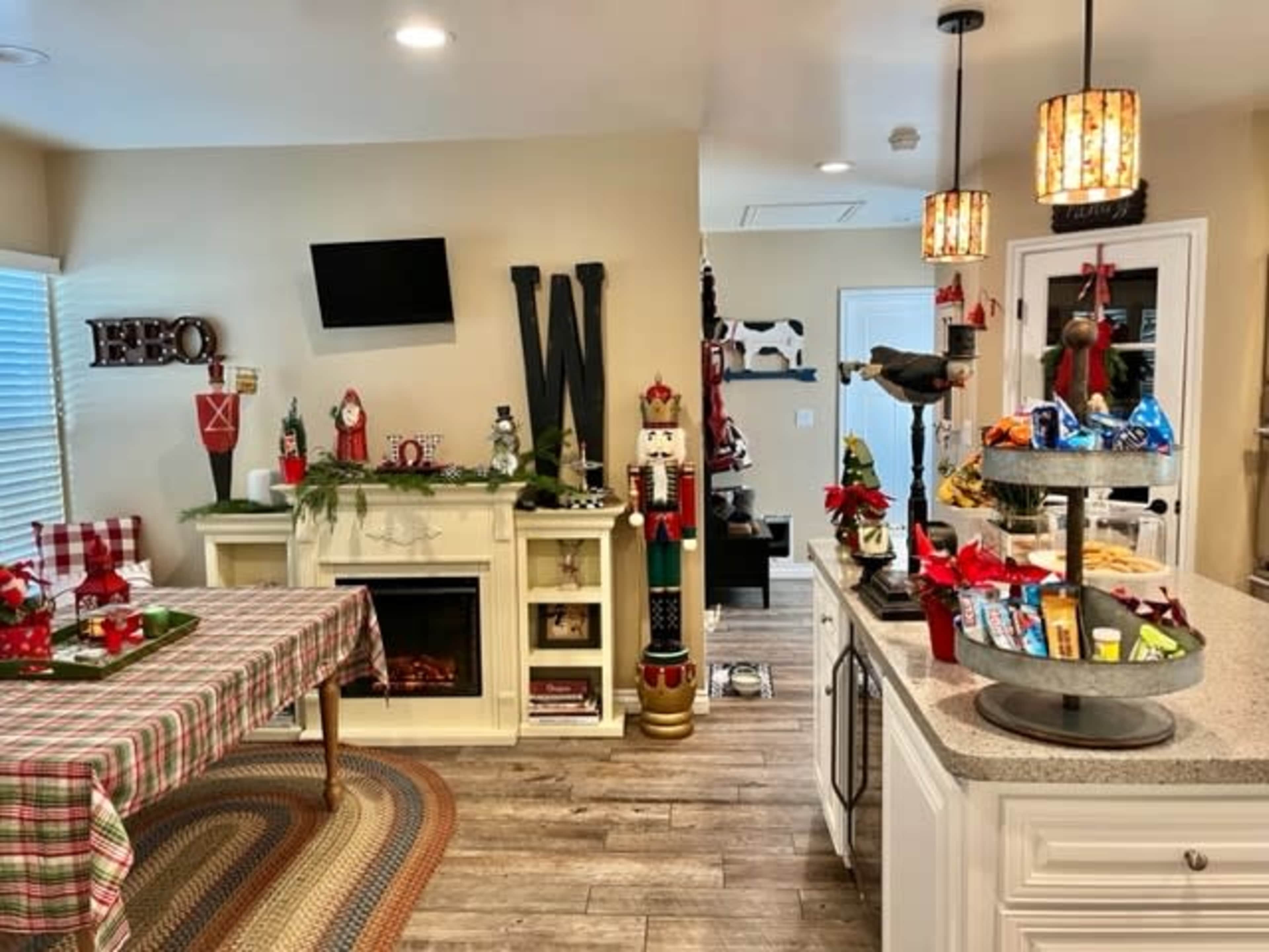 The scene shows a cozy kitchen and dining area decorated with Christmas-themed items, including a festive table, a nutcracker figurine, and various holiday decorations on the counter.