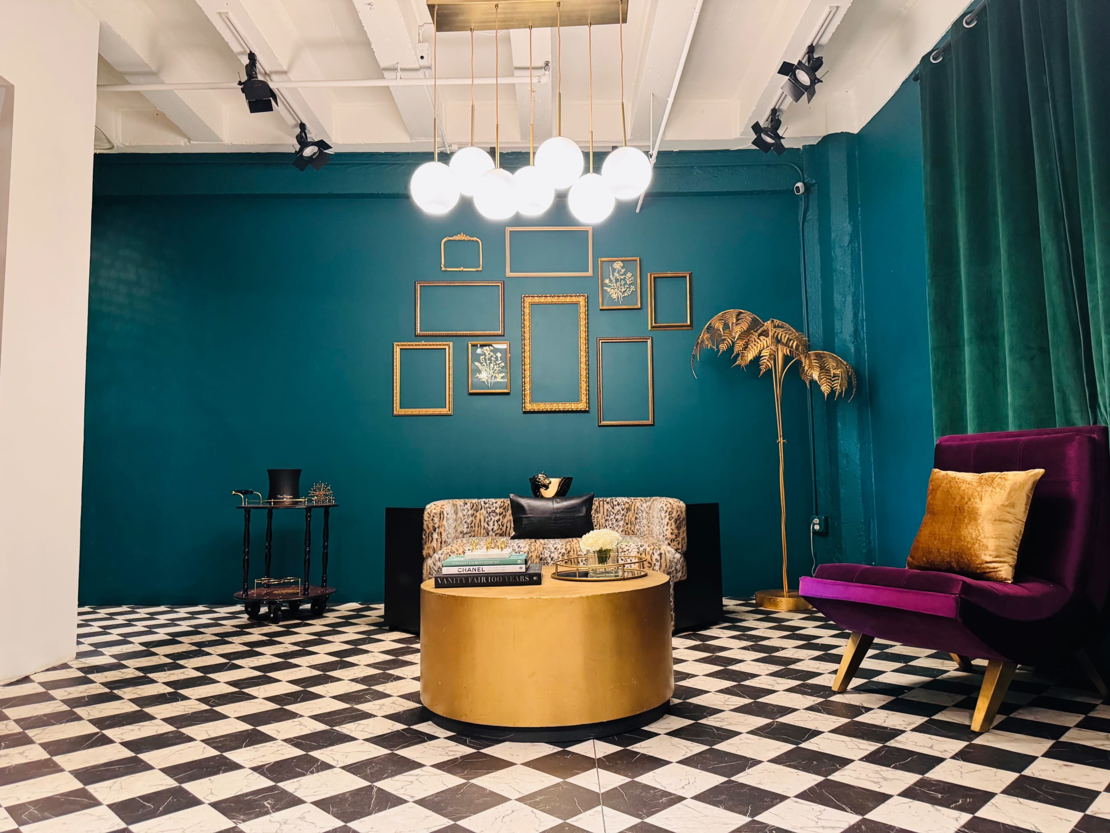 The image shows a stylish interior with a green wall, a patterned floor, a round gold coffee table, a colorful couch, and a purple armchair.