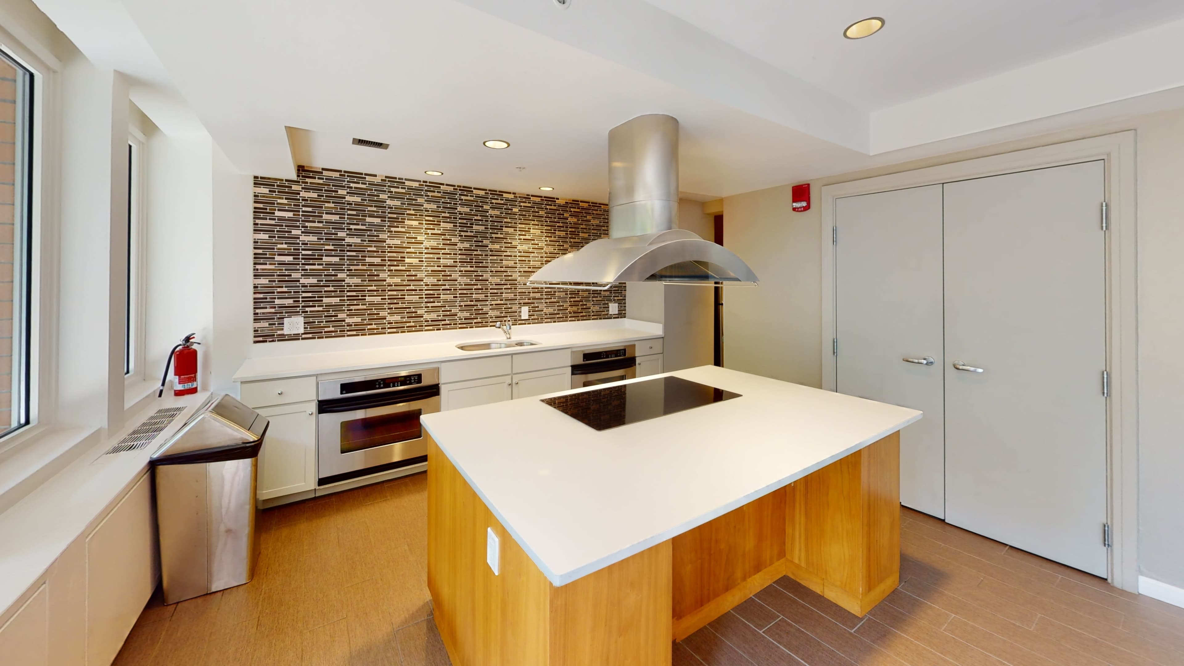 A modern kitchen with an island, stainless steel appliances, and a tiled backsplash.