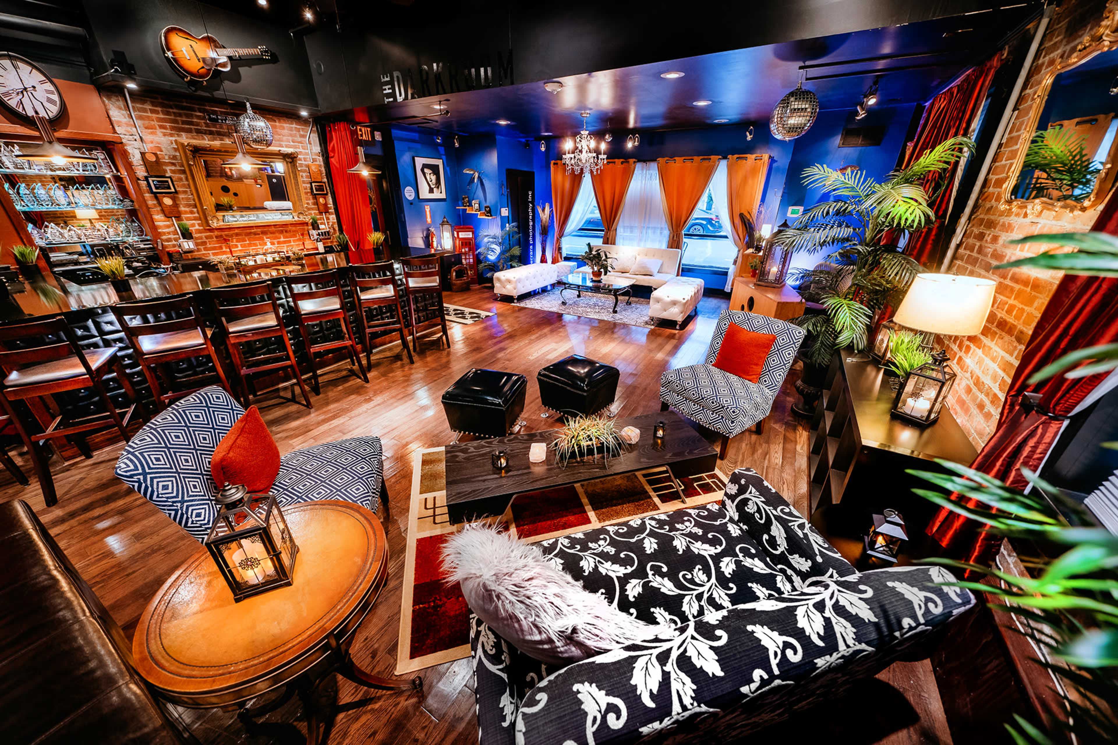 A stylish, modern lounge featuring a combination of seating options, a bar area, and decorative lighting.