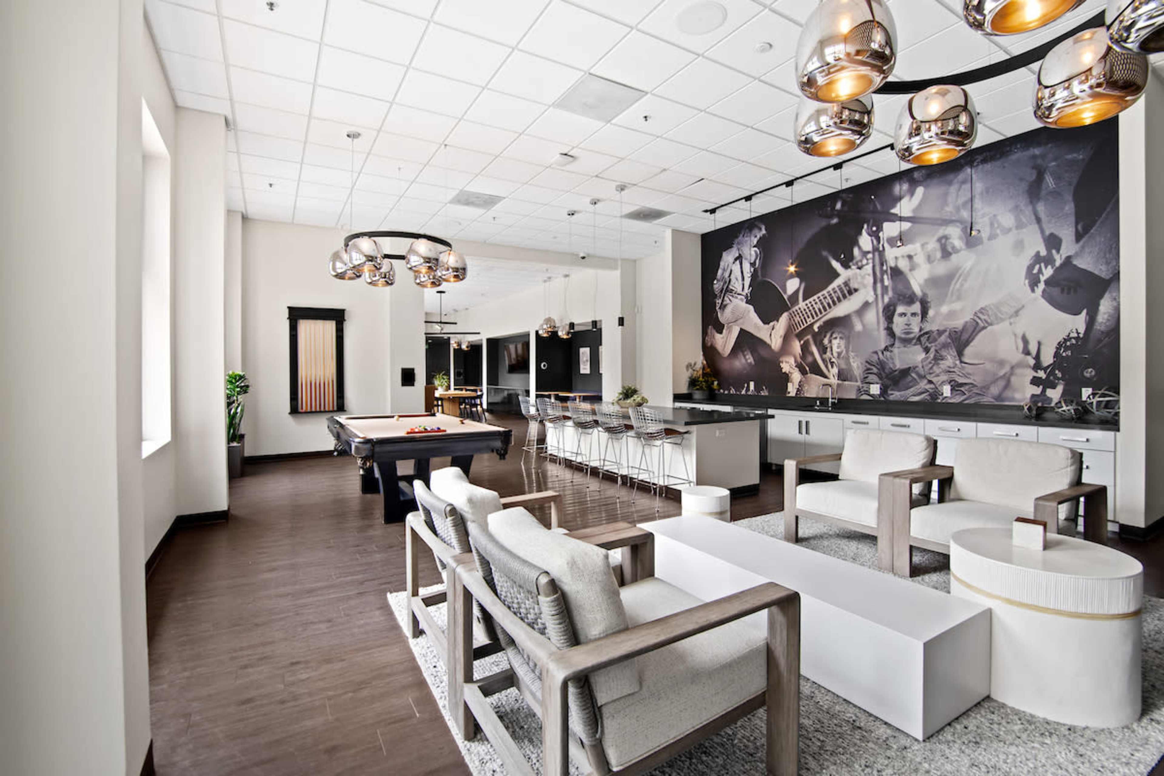 The image depicts a stylish leisure room featuring a pool table, modern seating, and a large mural of musicians on the wall.