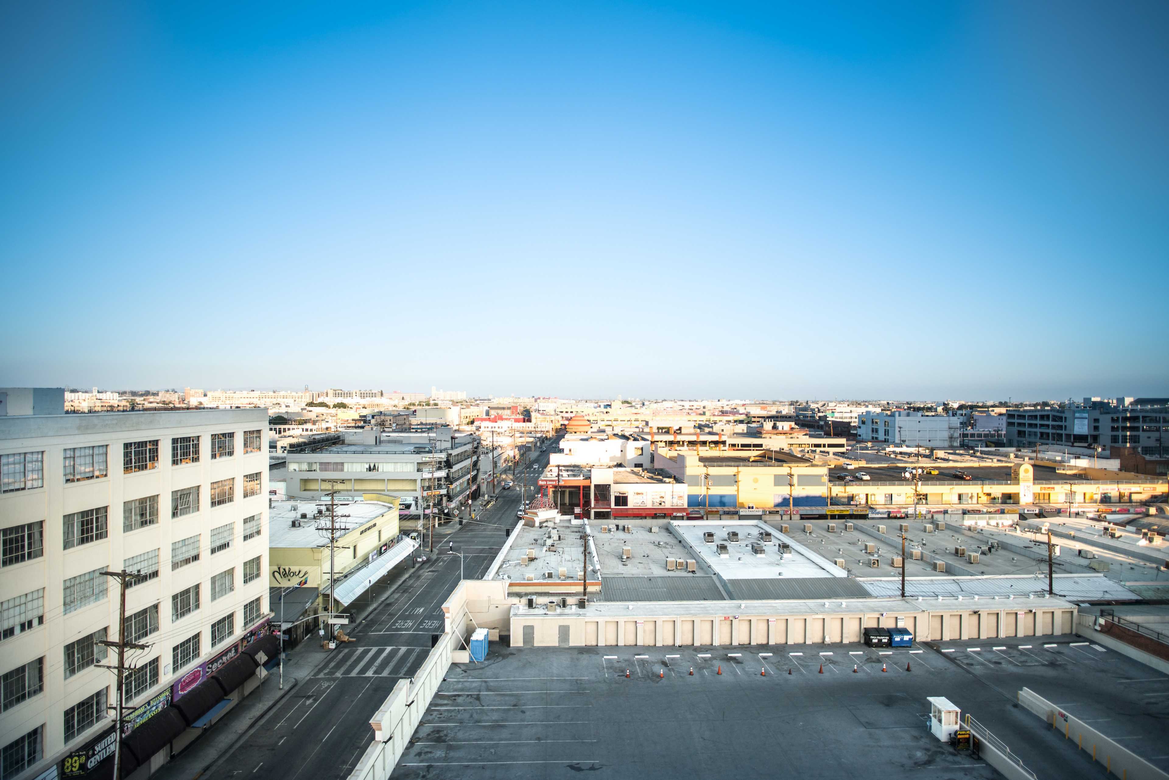 A wide view of a cityscape featuring industrial buildings, streets, and parking lots under a clear sky.