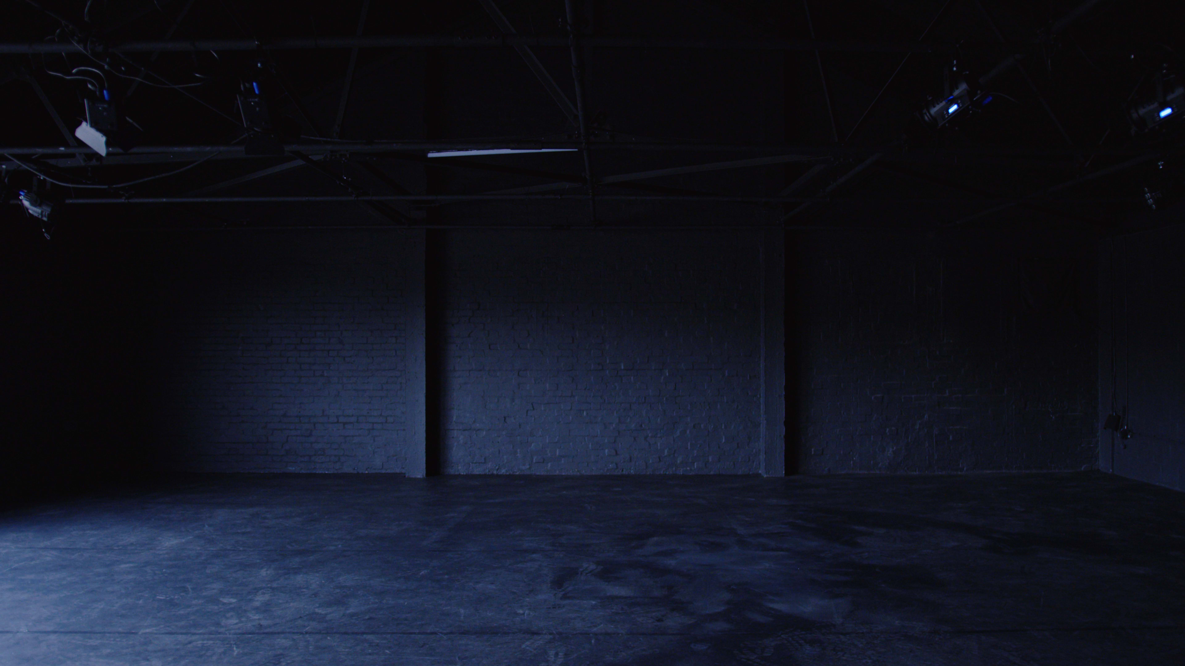 A dimly lit industrial space with exposed beams and dark walls.
