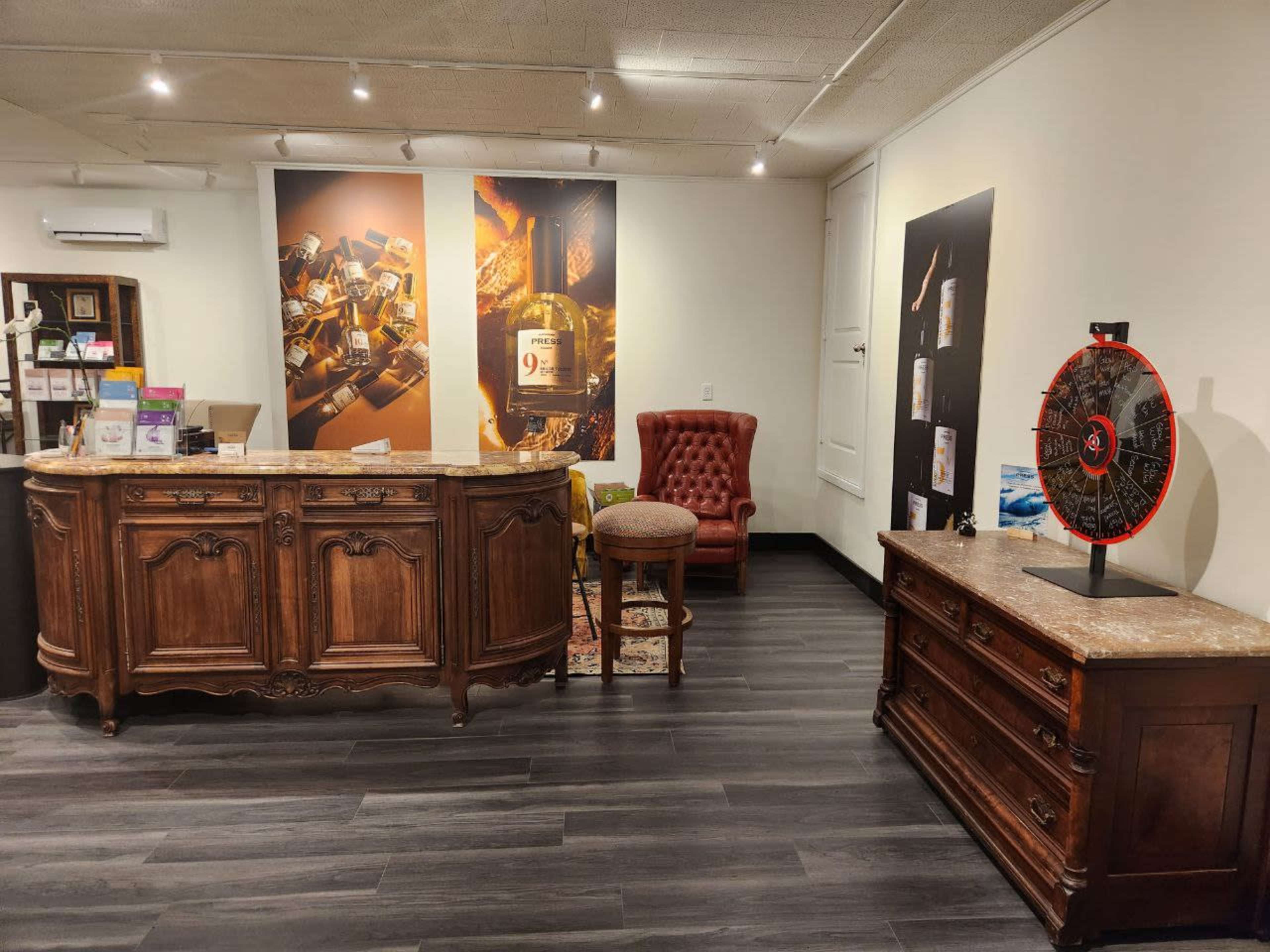 A reception area with a wooden front desk, a red upholstered chair, and decorative wall art featuring various products.