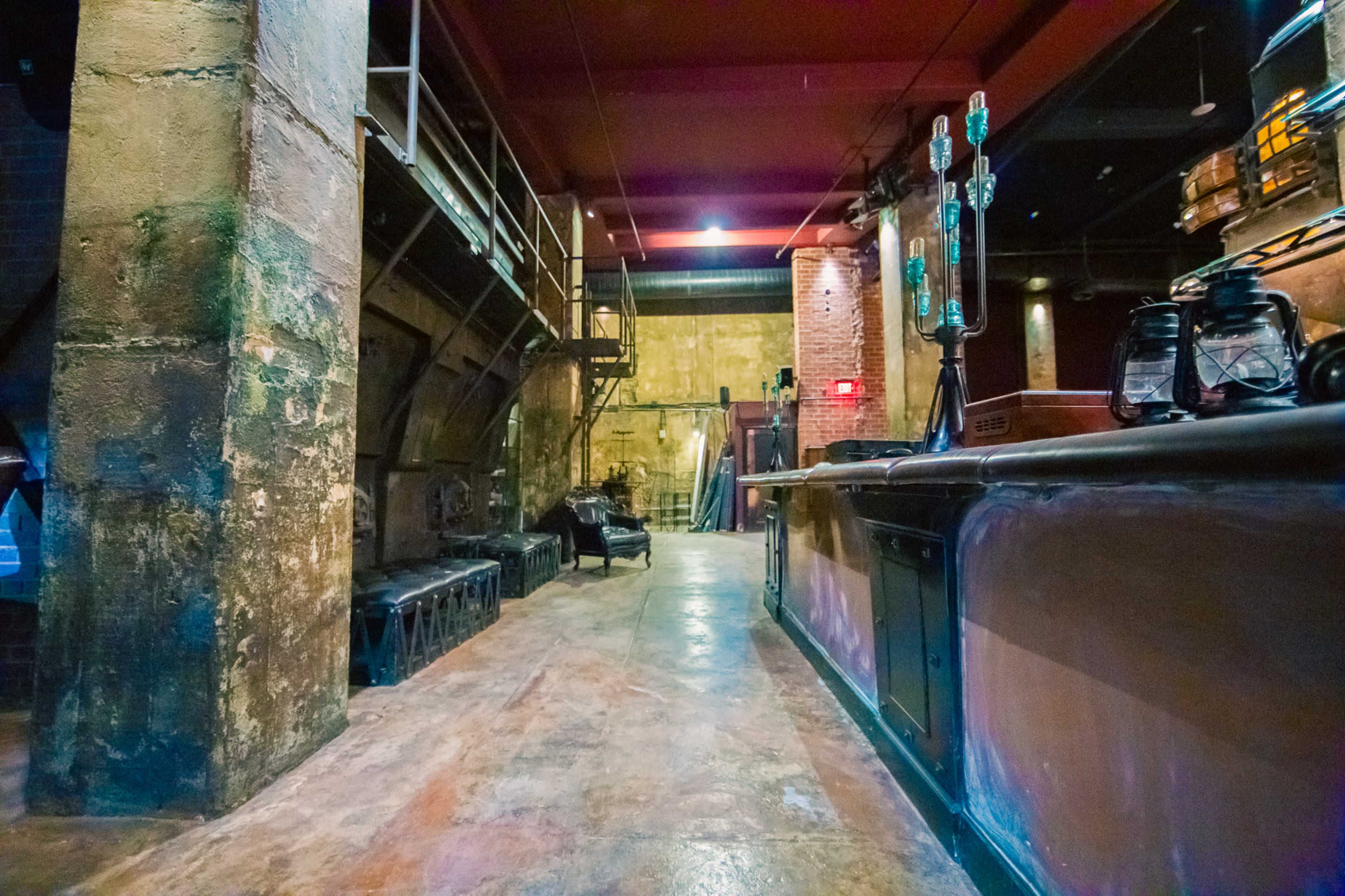 The image depicts an industrial bar interior with exposed brick walls, concrete floors, and metal reinforcements.
