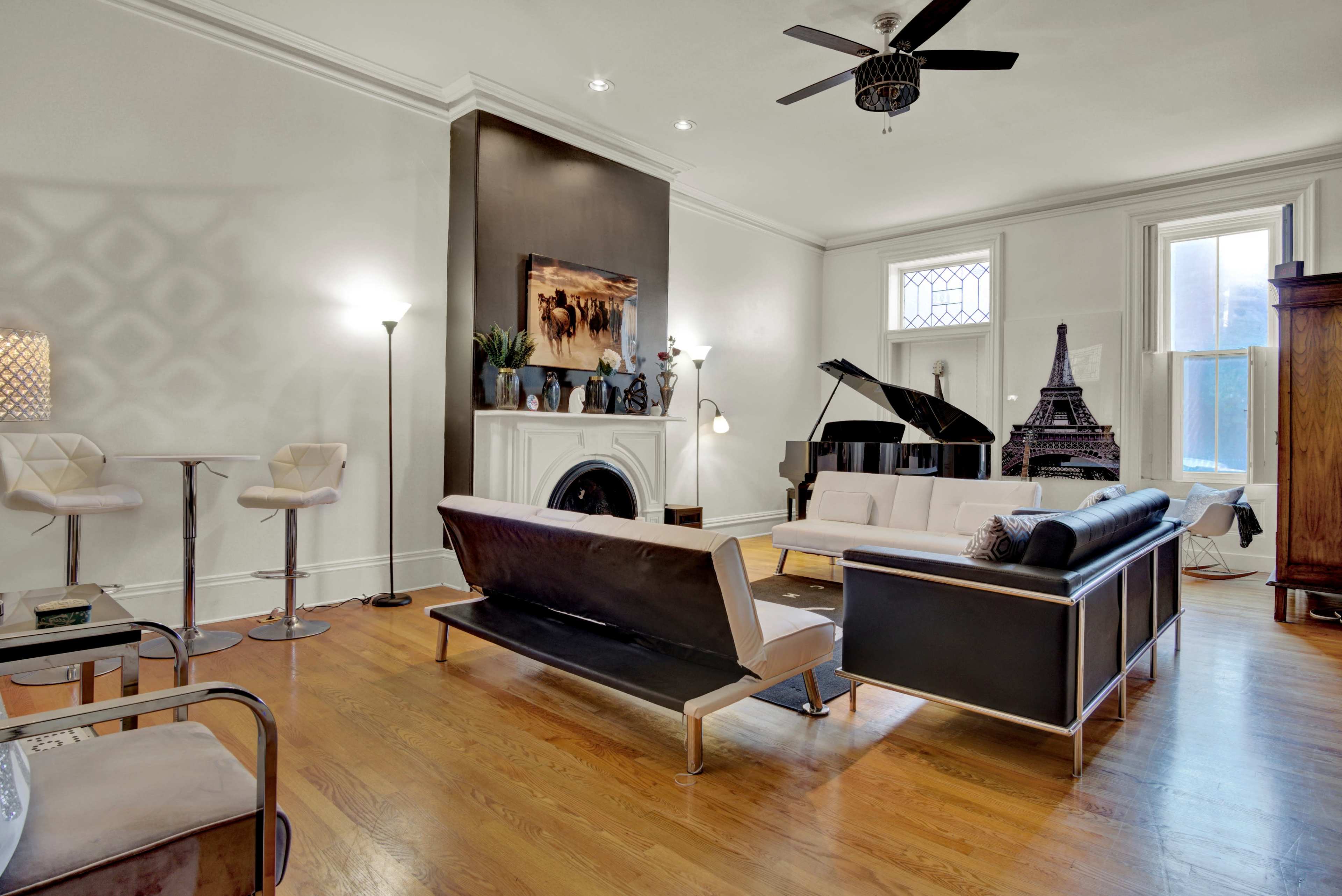 The living room features a black and white color scheme, a grand piano, an Eiffel Tower replica, and modern furniture arranged around a fireplace.
