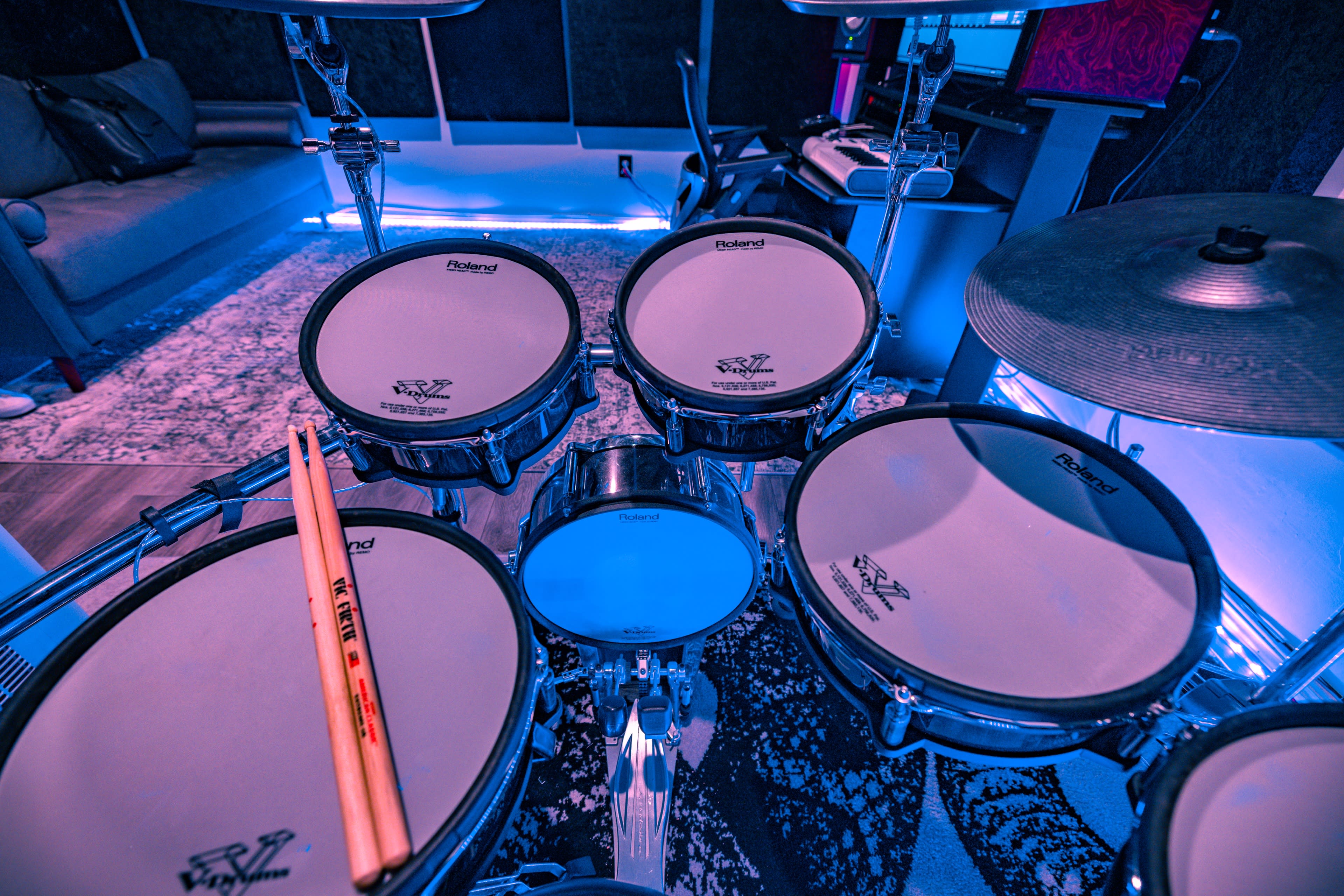A close-up view of a drum set featuring electronic drum pads, a cymbal, and drumsticks resting on one of the pads.