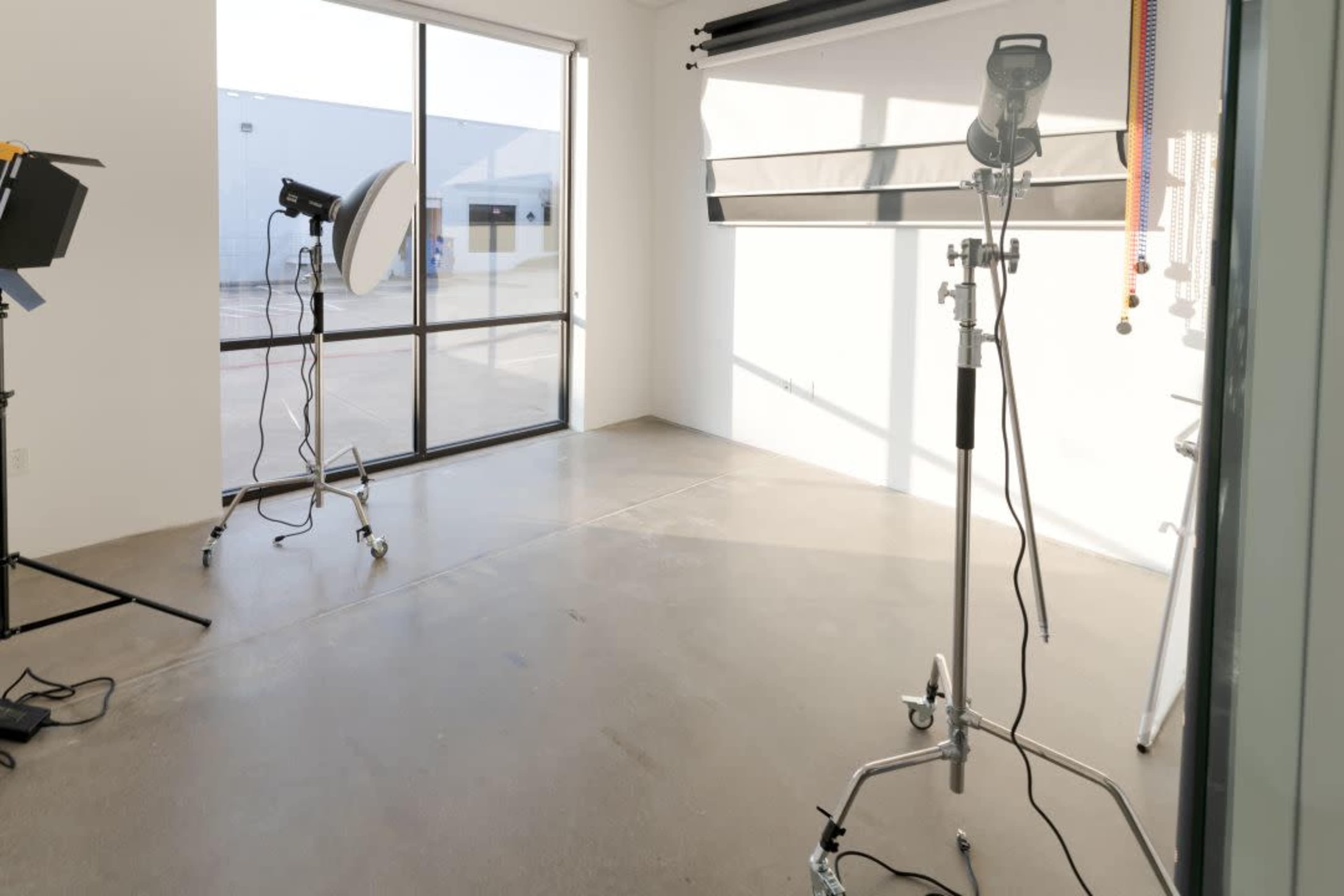 A well-lit photography studio with soft lighting equipment and a large window.
