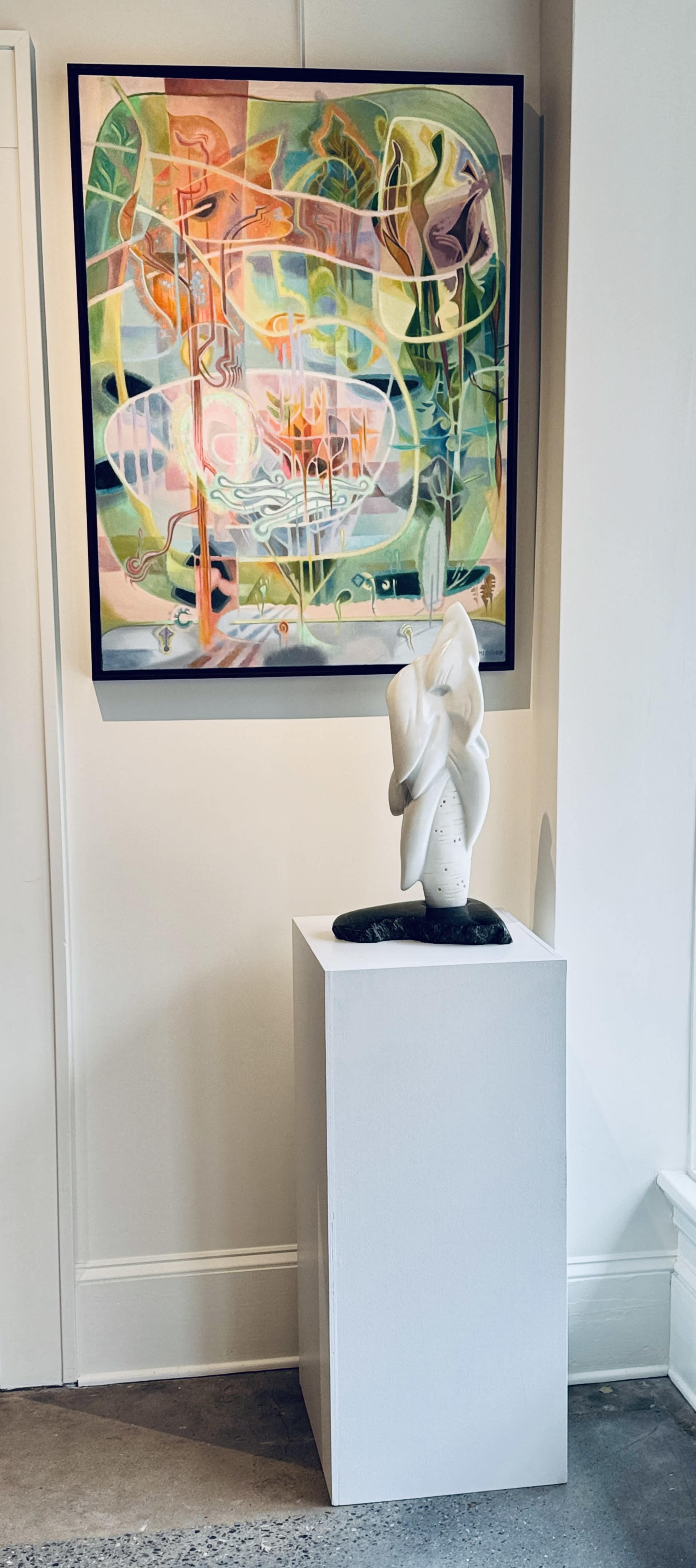 The image shows a modern art gallery featuring a colorful abstract painting on the wall and a white sculptural piece displayed on a pedestal nearby.