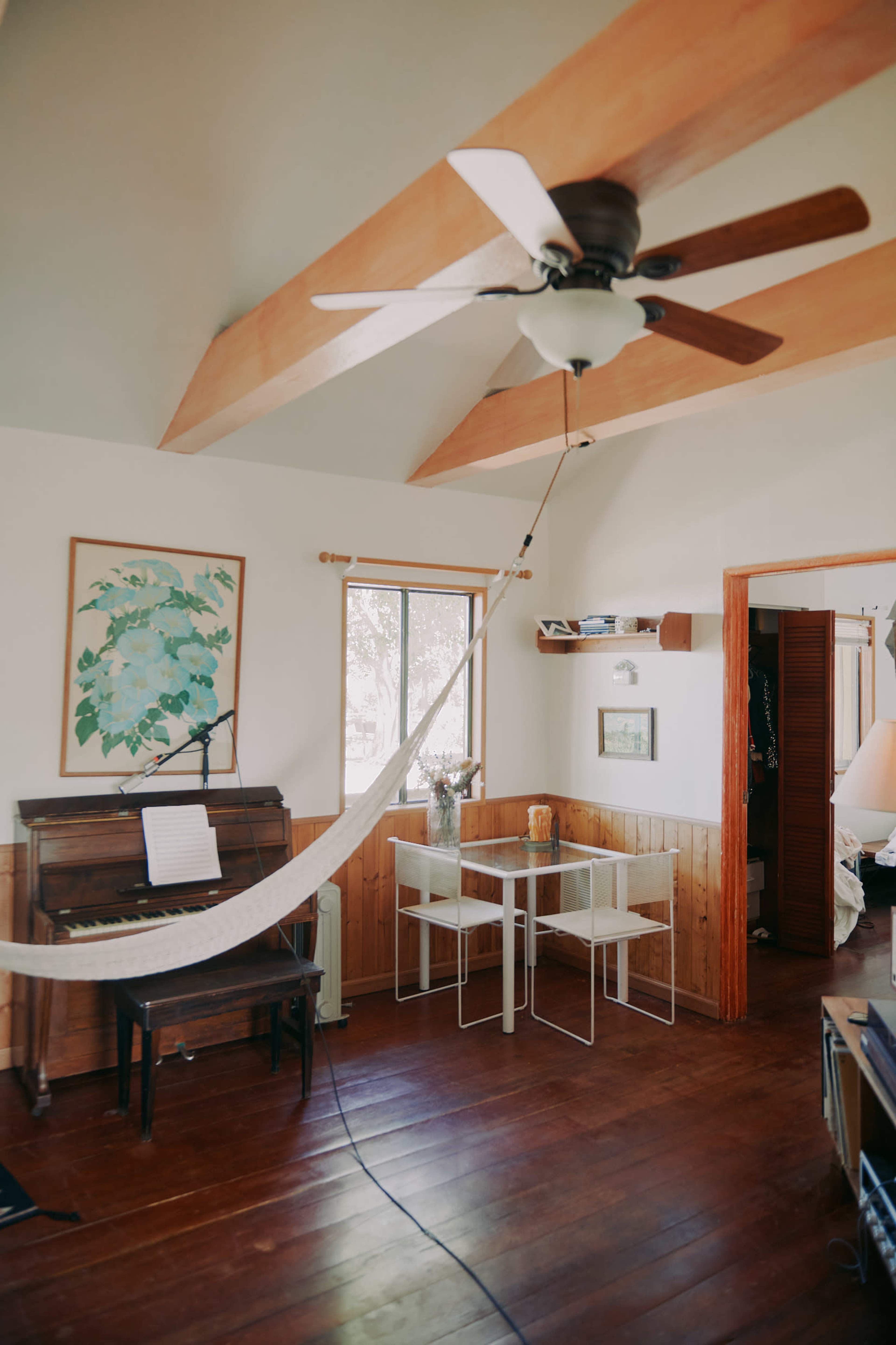 A spacious room features a piano, a dining table with clear chairs, and large windows that allow natural light to enter.