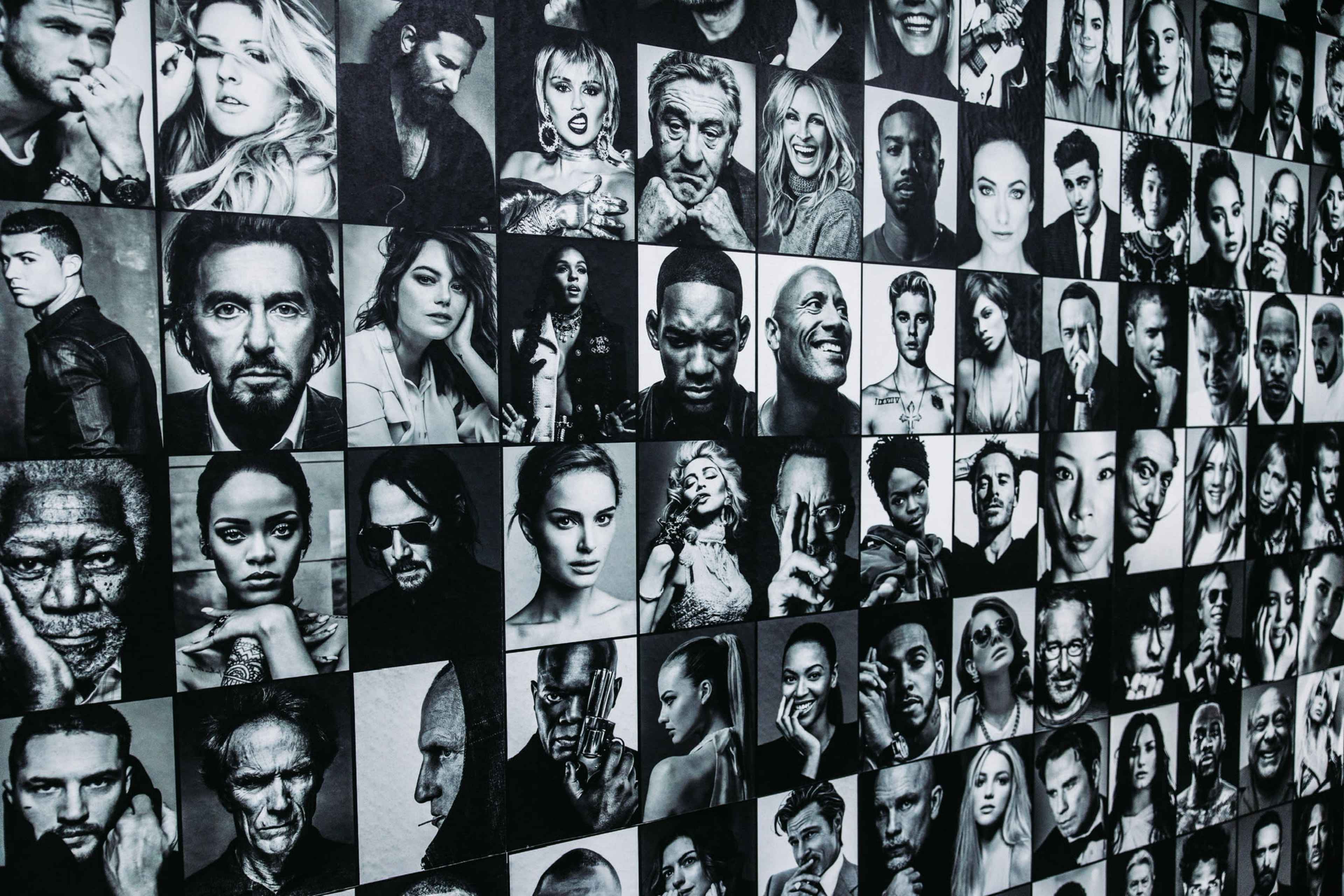 A collage of black and white portraits of various individuals displayed on a wall.