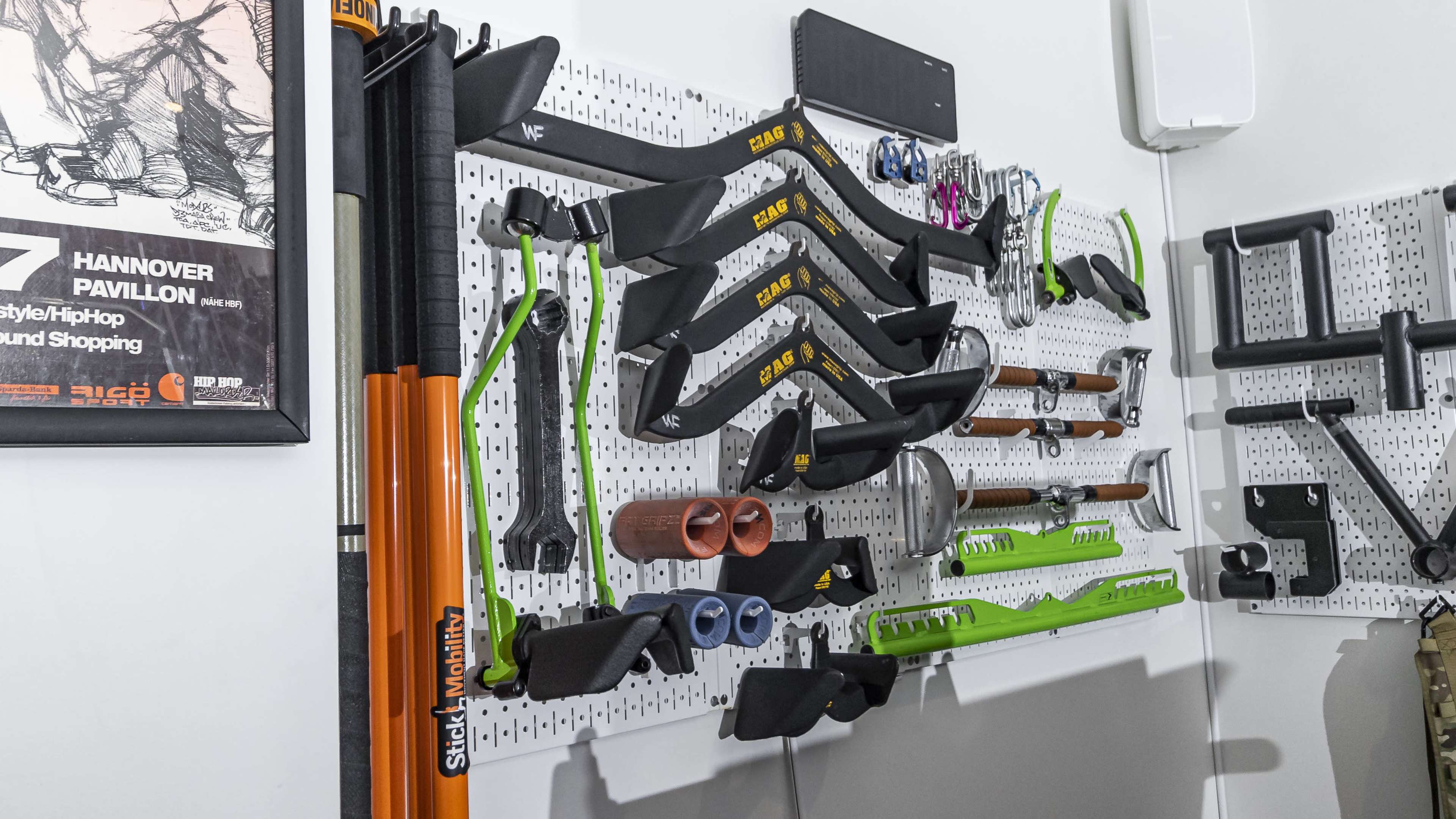 A pegboard wall organized with various gardening and hand tools, including hoes, shovels, and clamps, alongside colorful accessories.