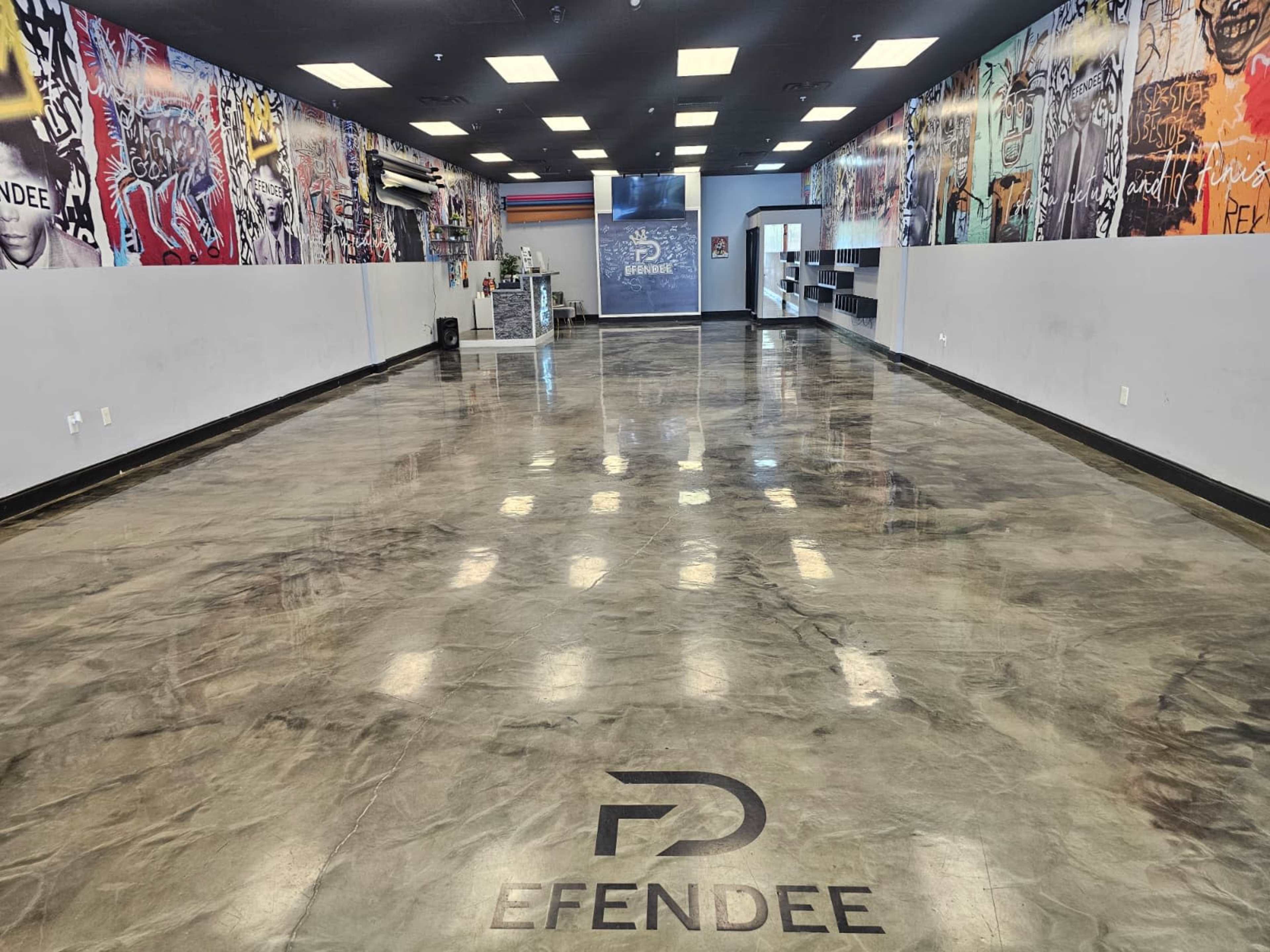 The image shows a spacious, empty interior of a store with polished concrete floors and colorful wall murals.