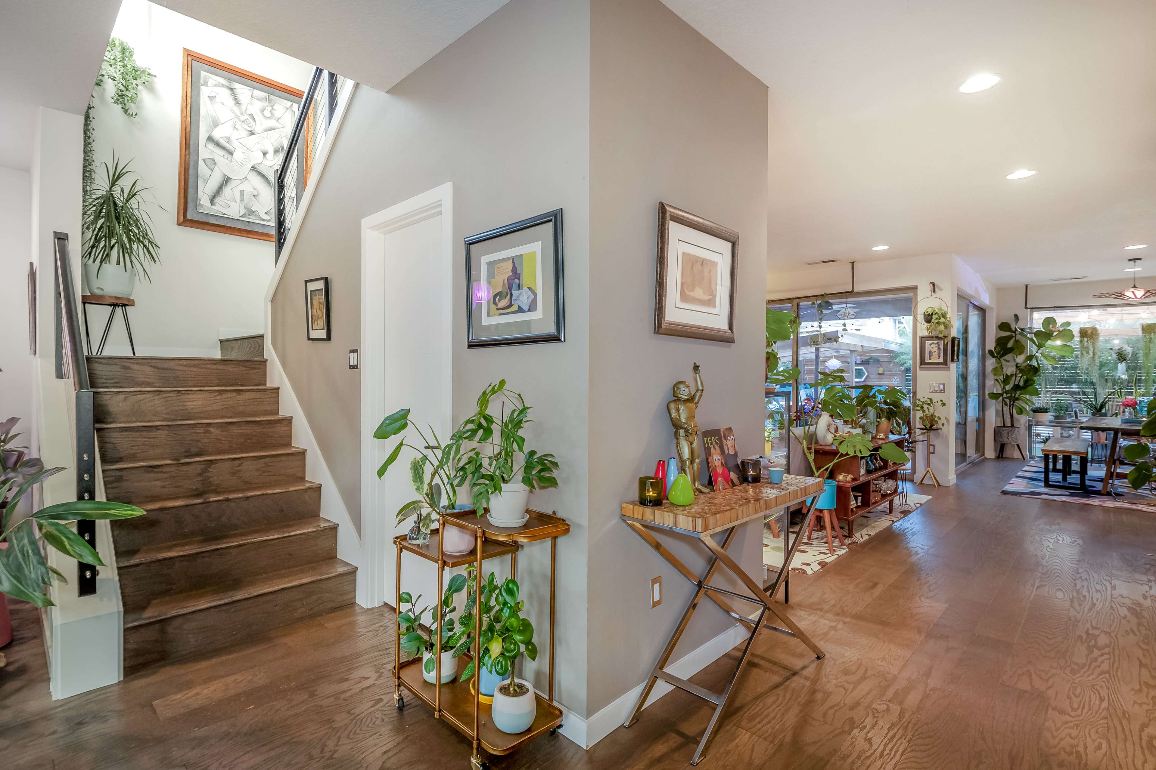 A spacious entryway features a staircase, plants, and doorways leading to additional rooms.