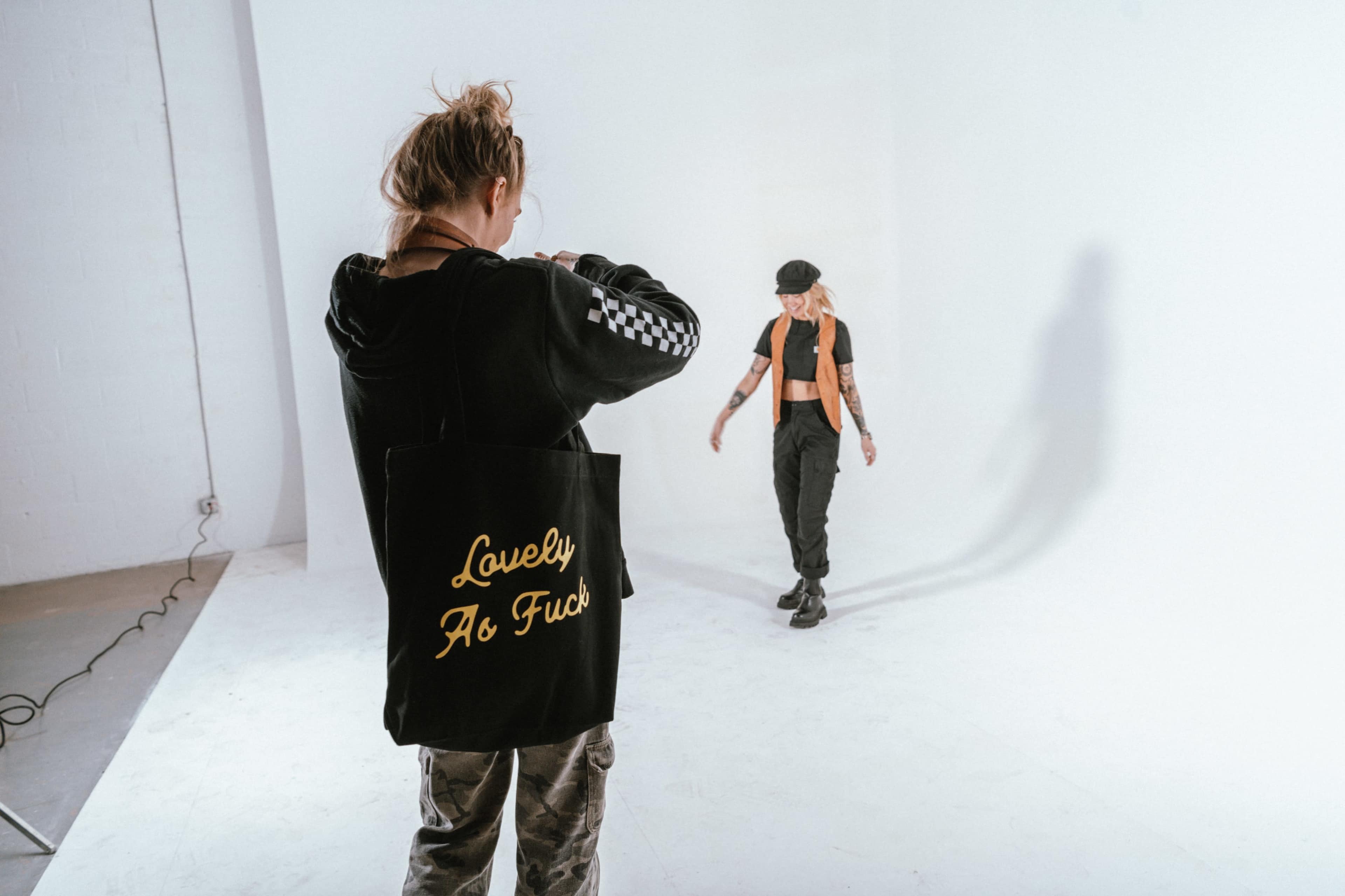 A photographer captures a model walking in a studio with a plain white backdrop.