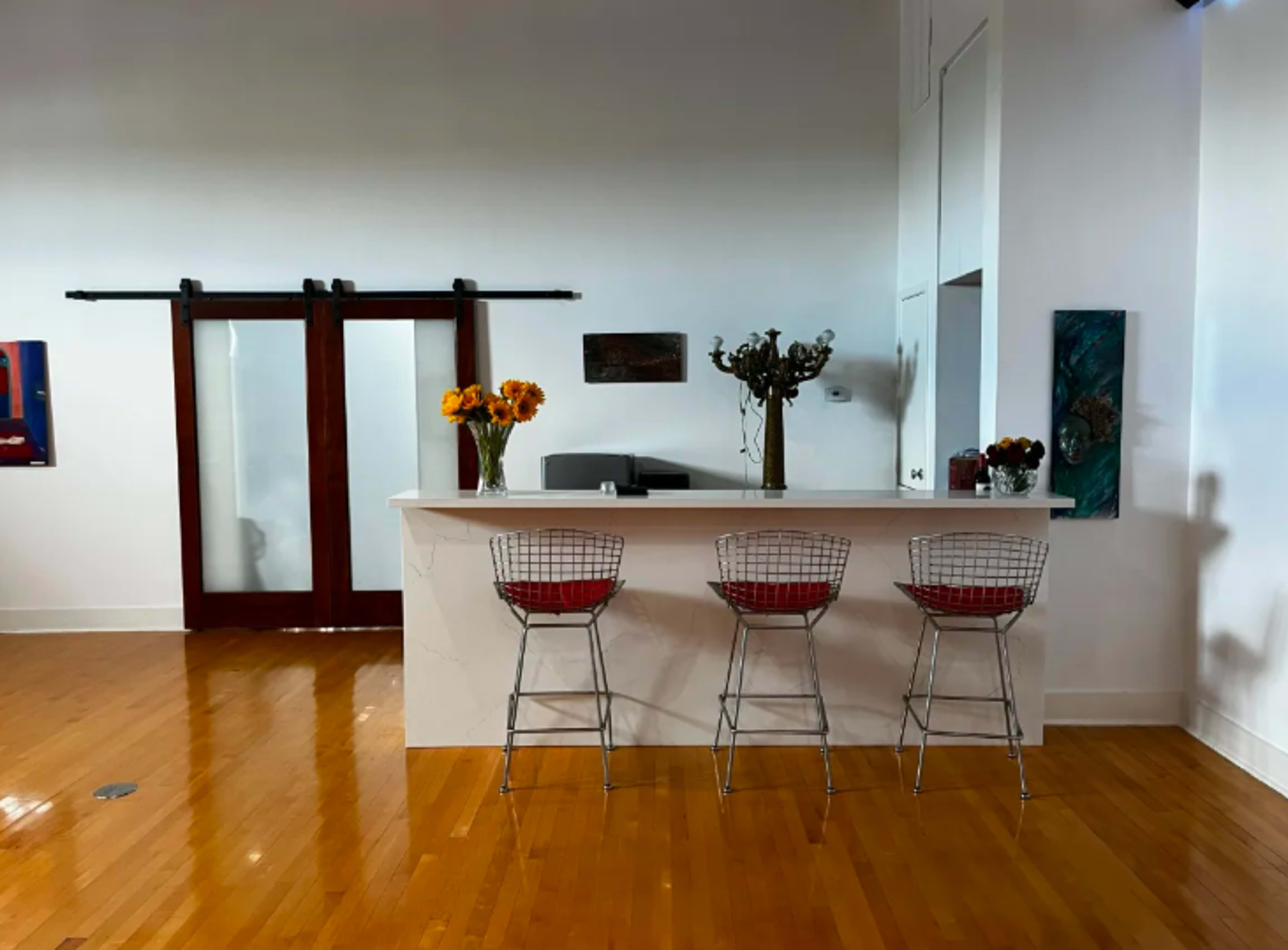 A modern kitchen features a sleek countertop with three wire bar stools and a backdrop of sliding doors.