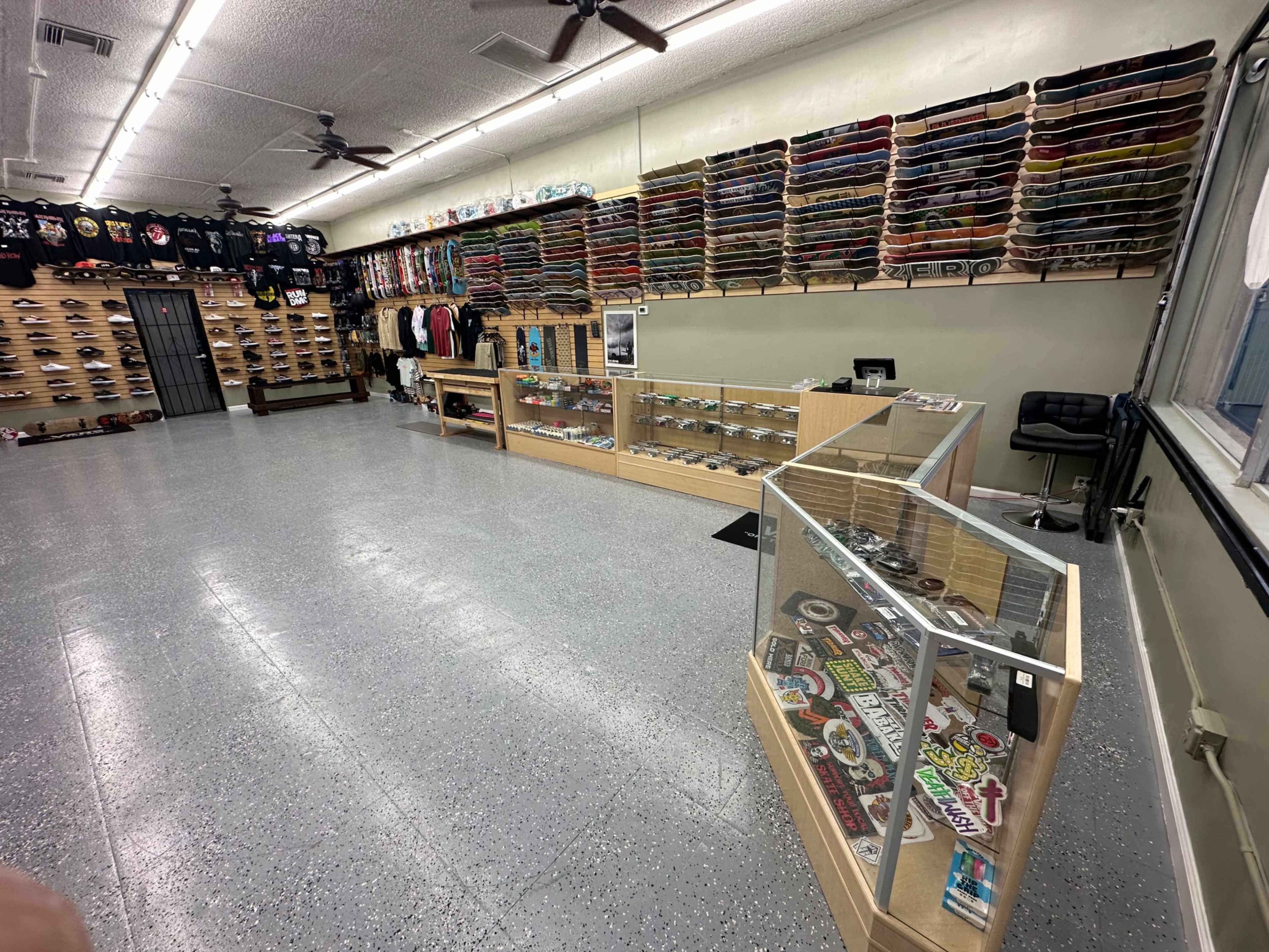 The interior of a retail store with skateboards displayed on wall racks and merchandise organized on shelves and glass display cases.