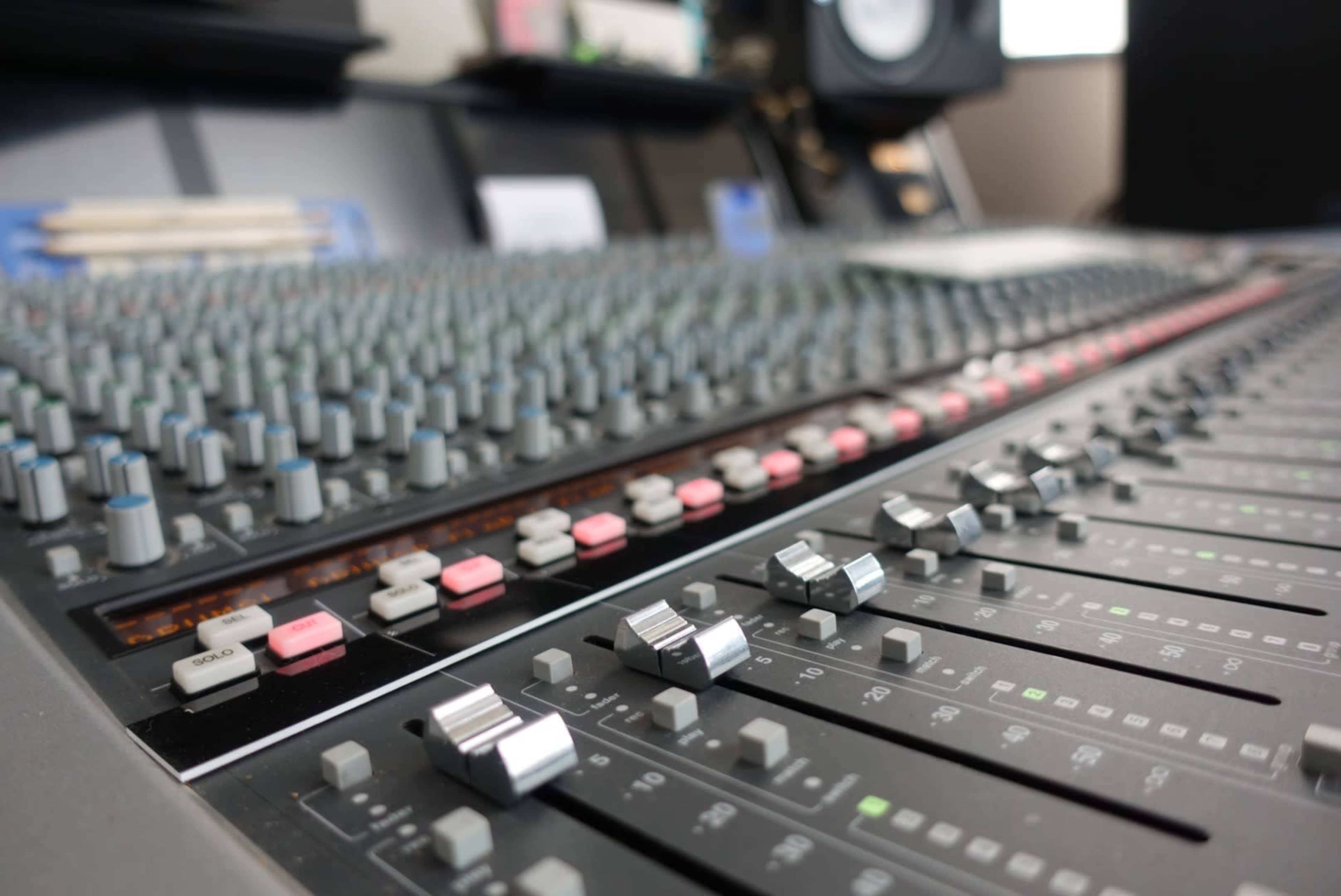 A close-up of a sound mixing console with various knobs and sliders.