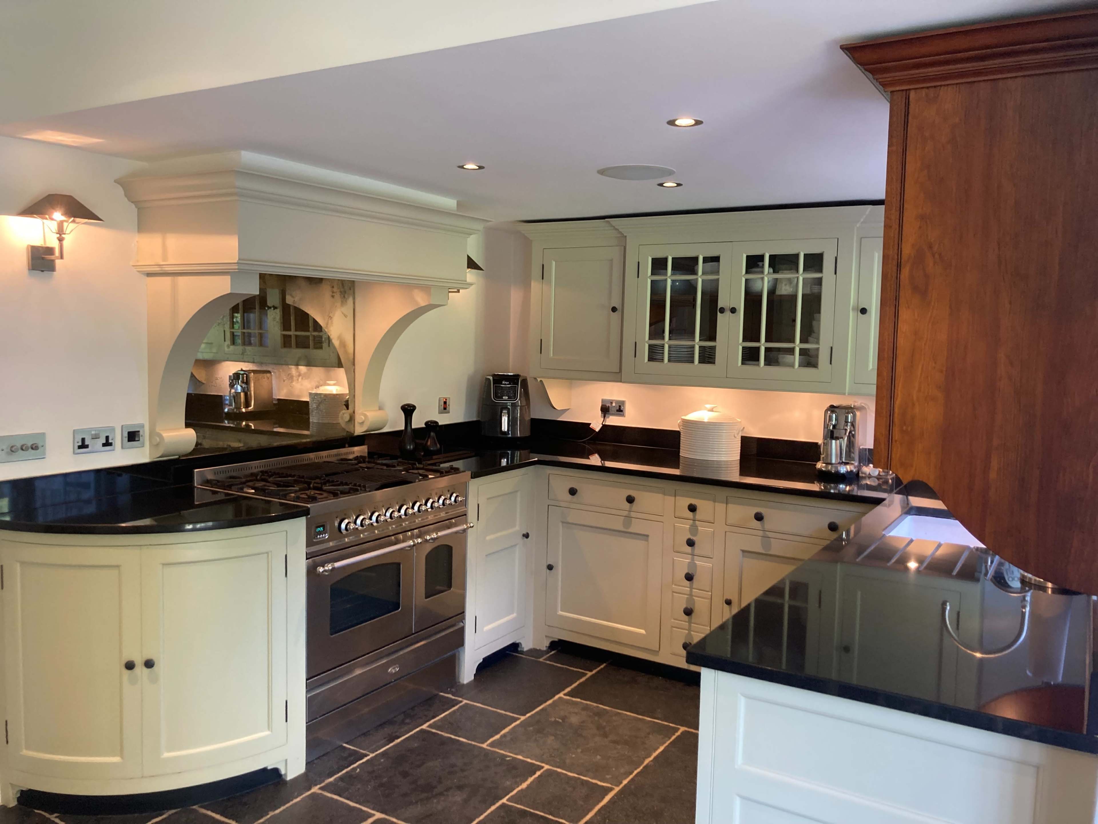 The kitchen features white cabinetry, a stainless steel range, dark countertops, and slate flooring.