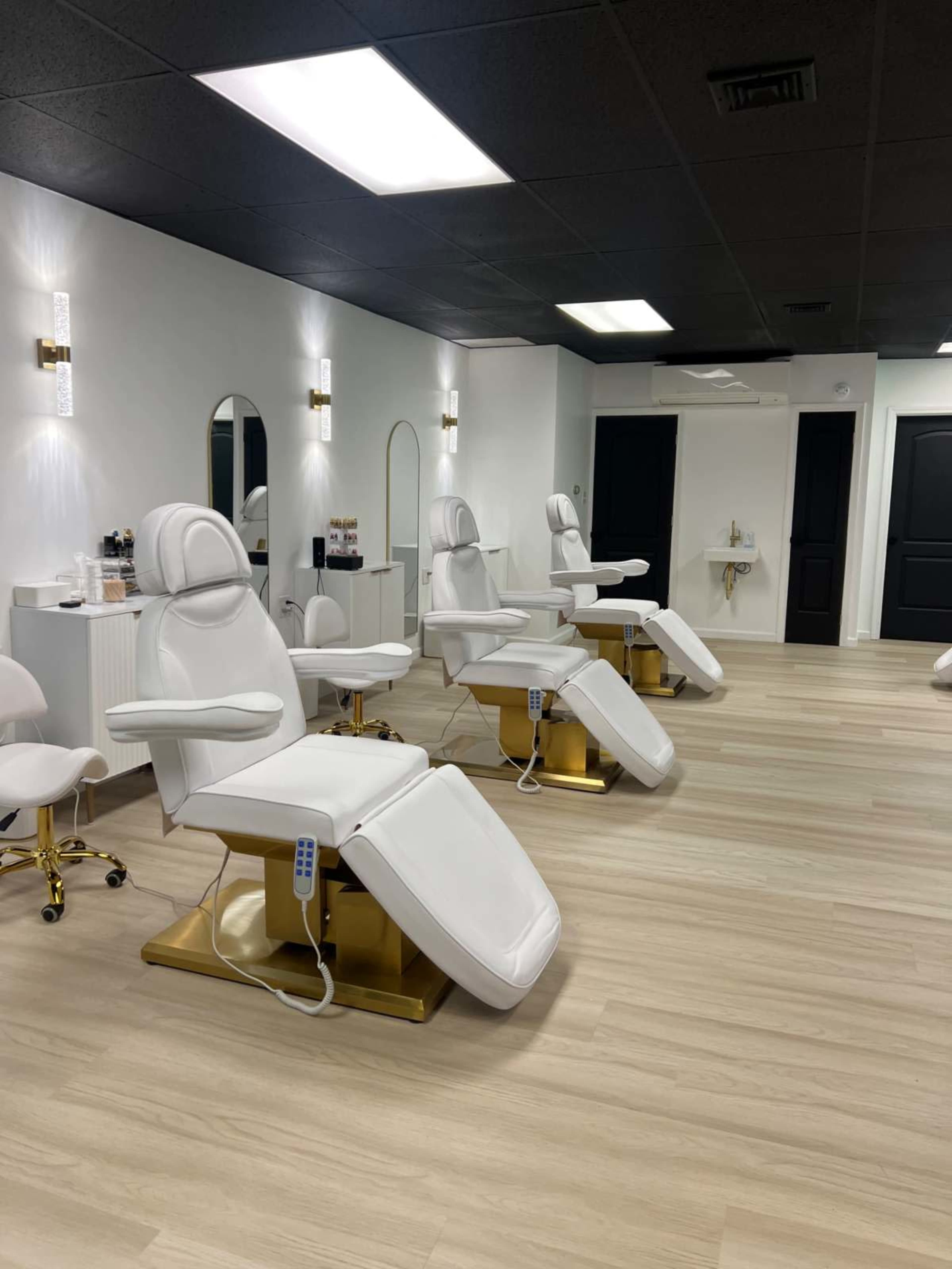 A modern salon interior with several white treatment chairs arranged neatly on a light wood floor.