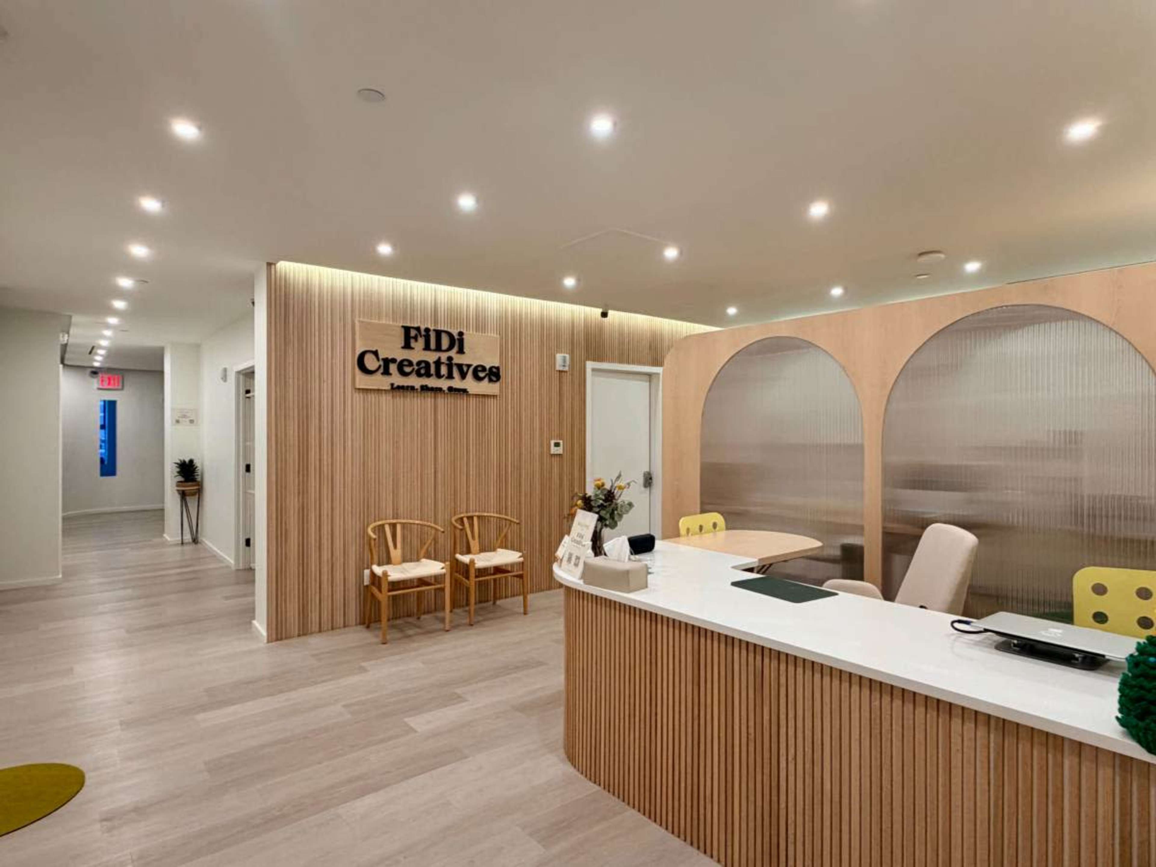 The image shows a modern office reception area featuring a wooden front desk, two chairs, and light-colored walls.