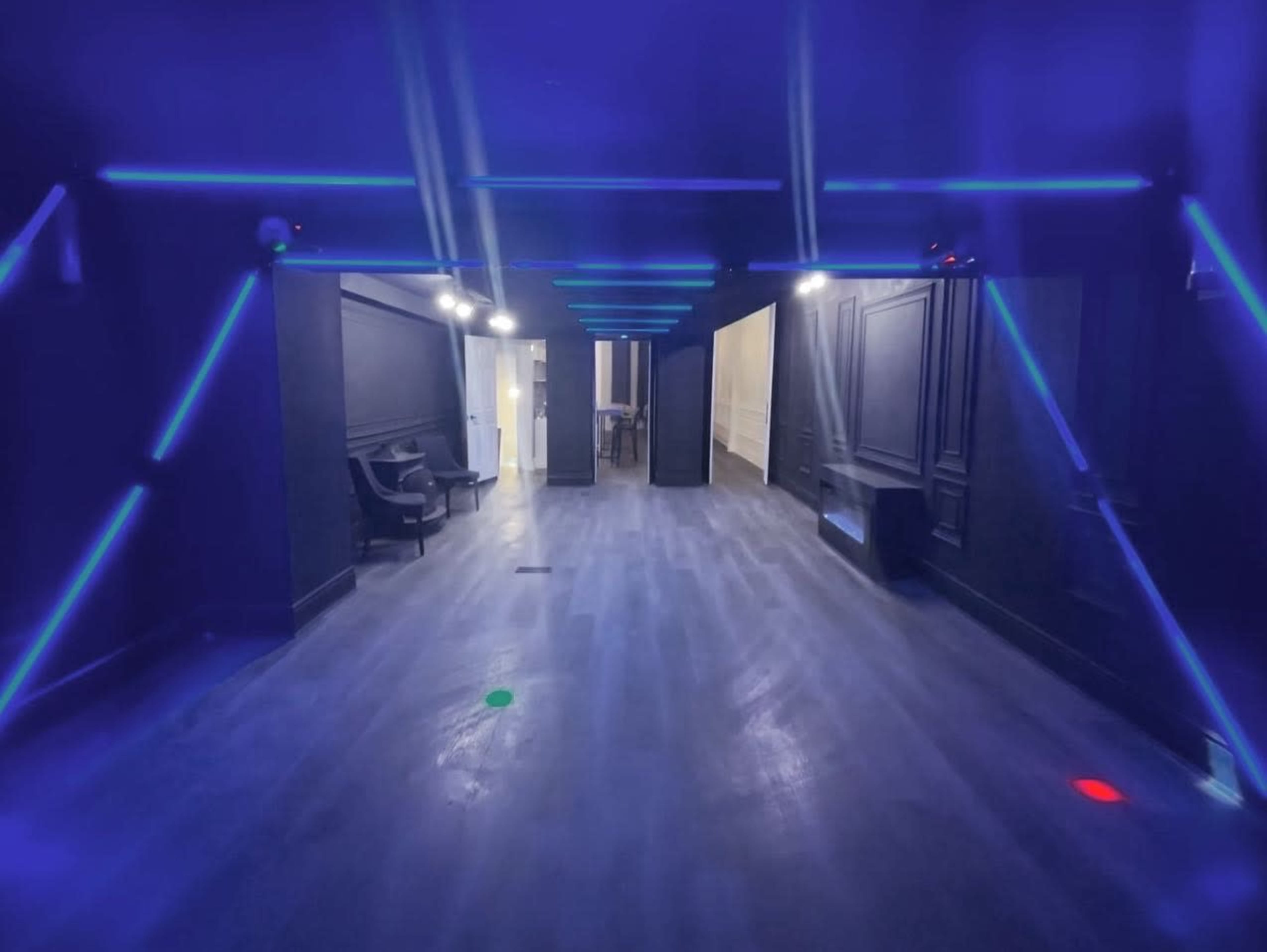 A dimly lit interior space featuring dark walls and floor, with blue neon lights angled towards the center of the room.
