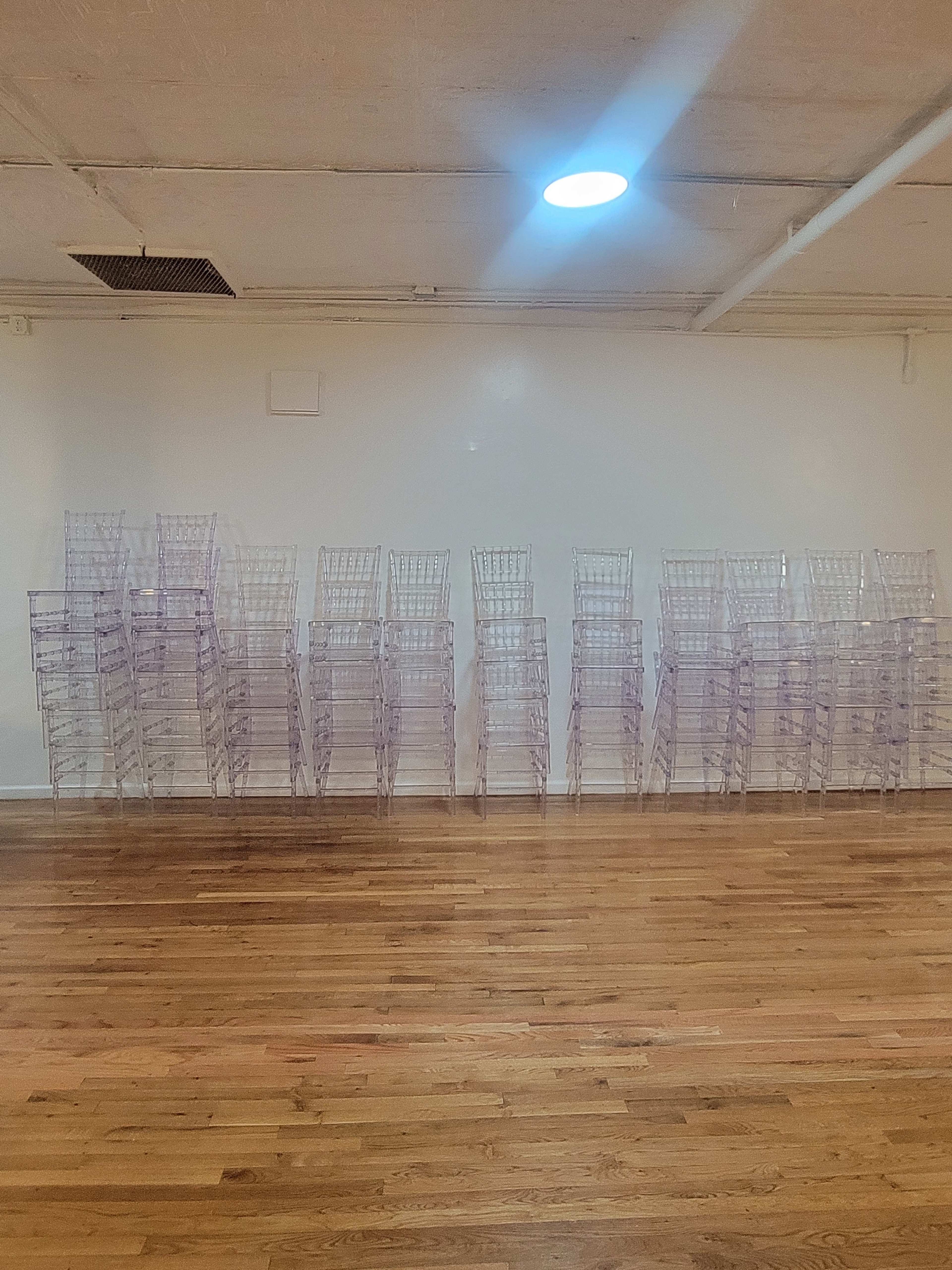 A wall of transparent plastic storage racks stacked in an organized manner against a white wall in a wooden-floored room.