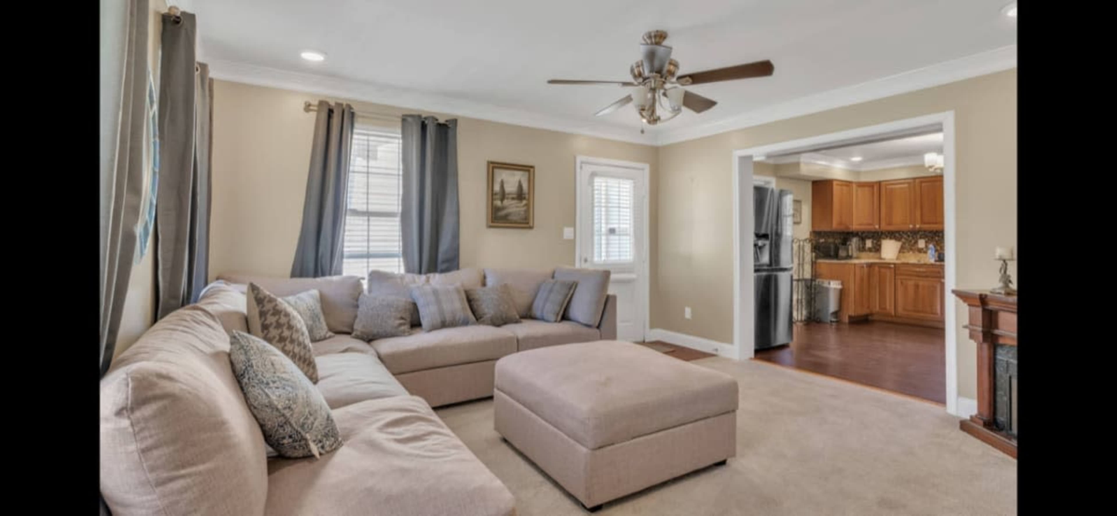 A living room with a sectional sofa, a coffee table, and a view into a kitchen with wooden cabinets.