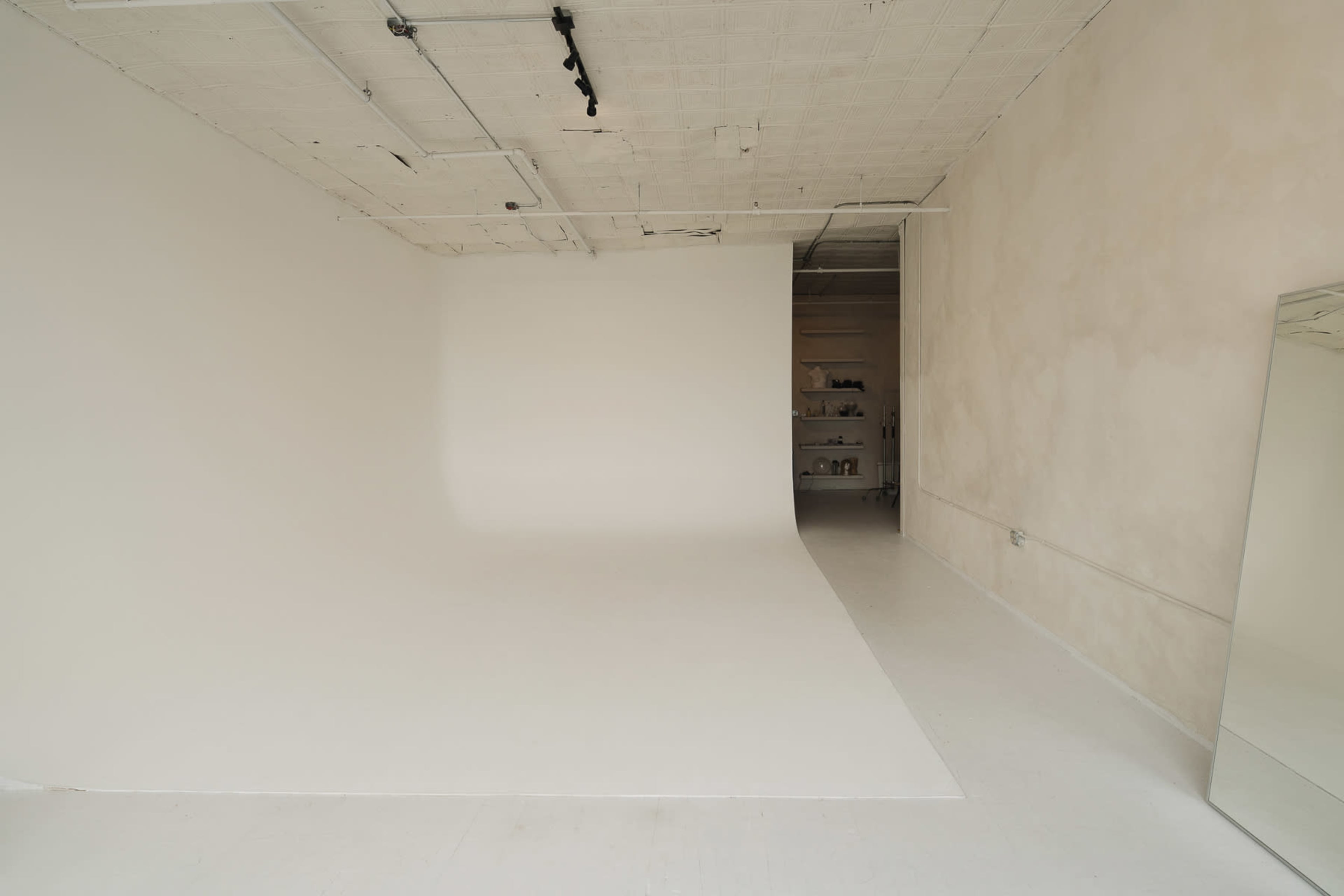 The image shows a spacious, minimalist studio with a white backdrop and simple decor.
