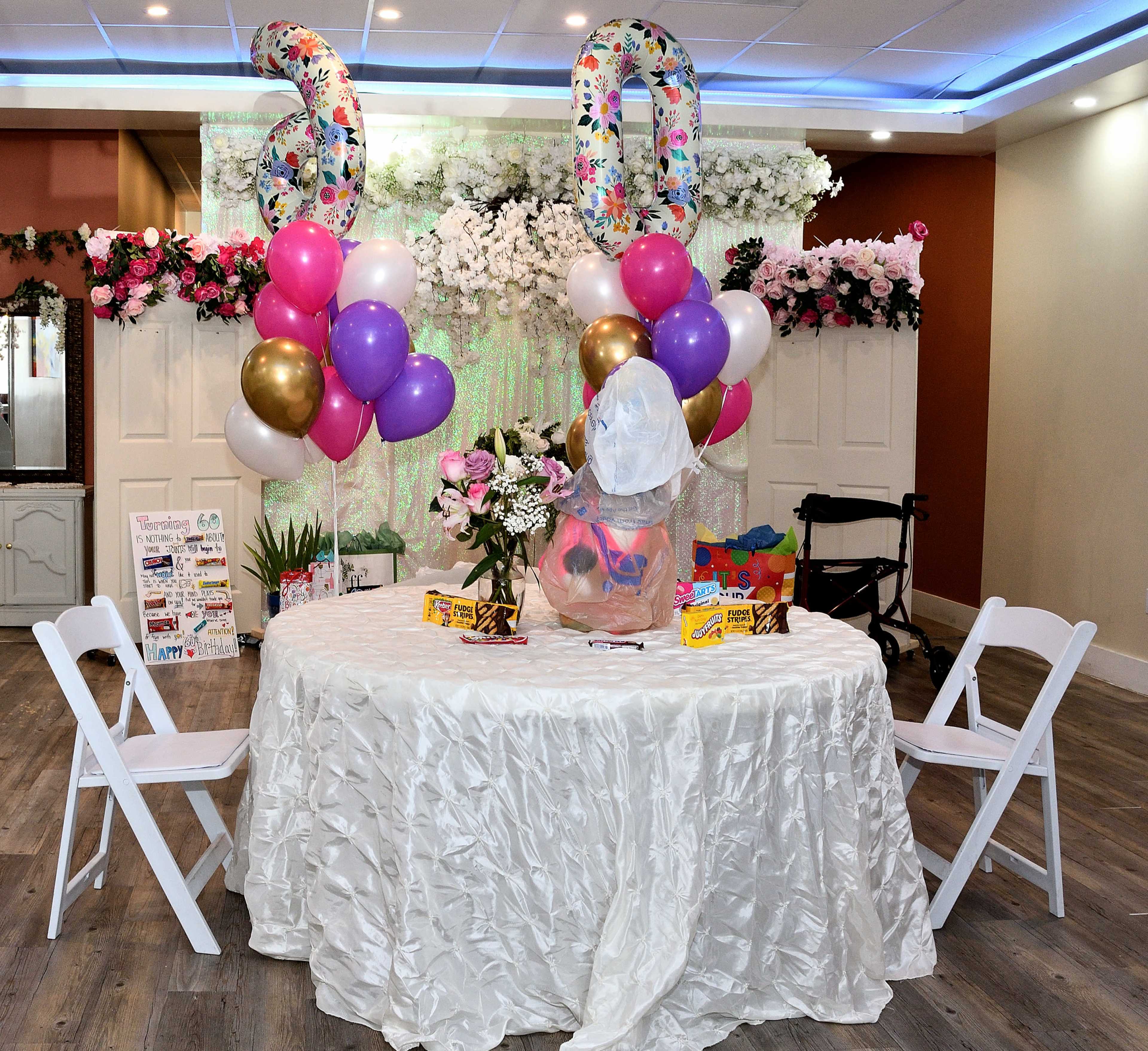 The image shows a decorated table with a white tablecloth, balloons, a floral backdrop, and a "30" balloon centerpiece, set up for a celebration.