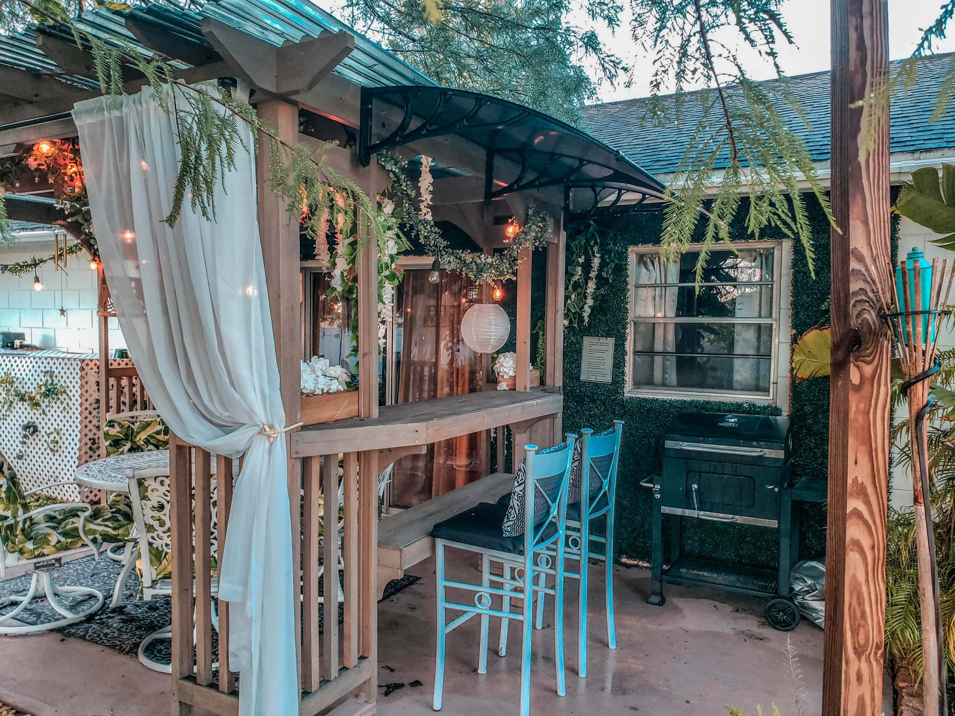 A cozy outdoor seating area with wooden furniture, decorative plants, and soft lighting.