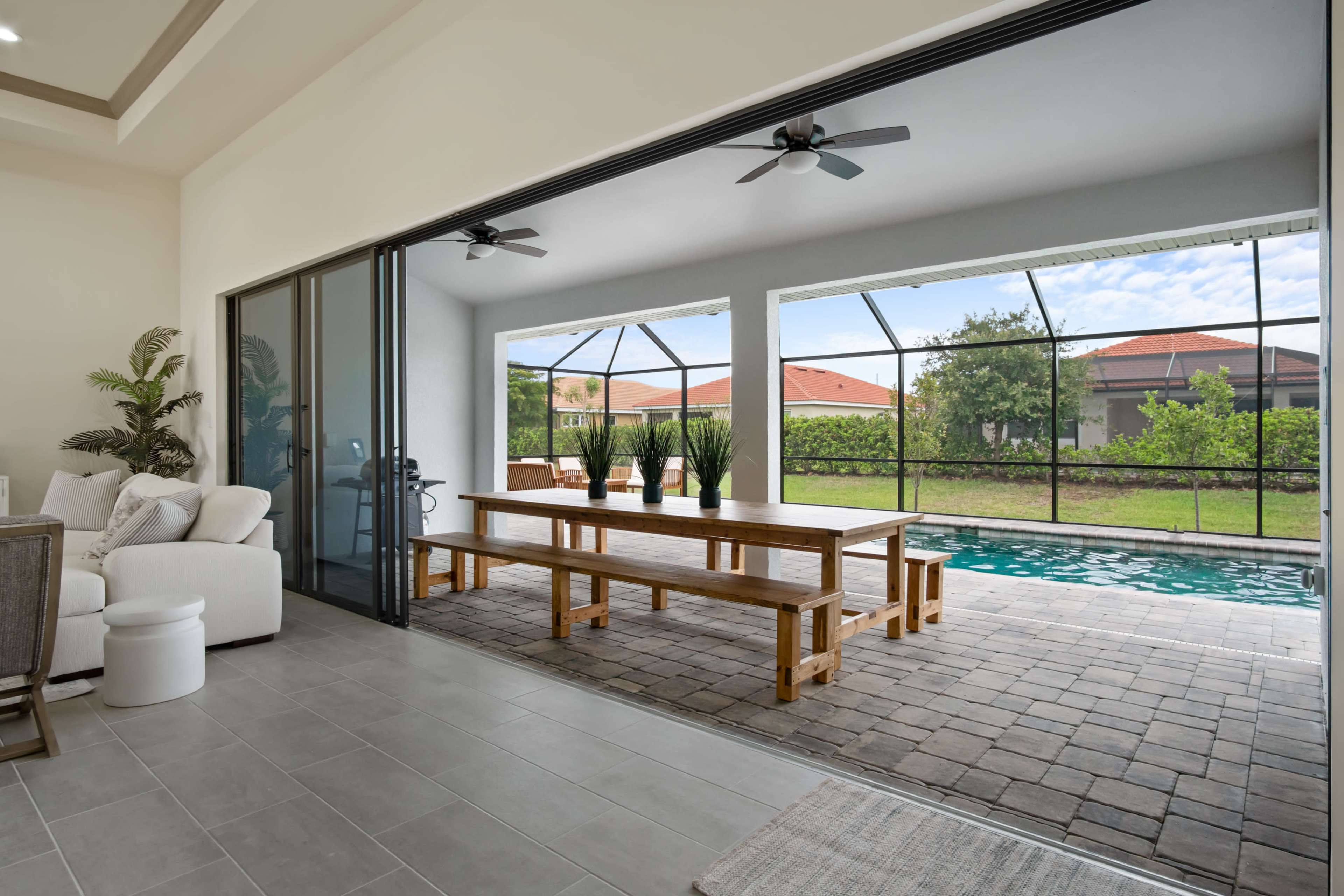 A modern living space with a large sliding glass door that opens to a patio with a swimming pool and outdoor seating area.