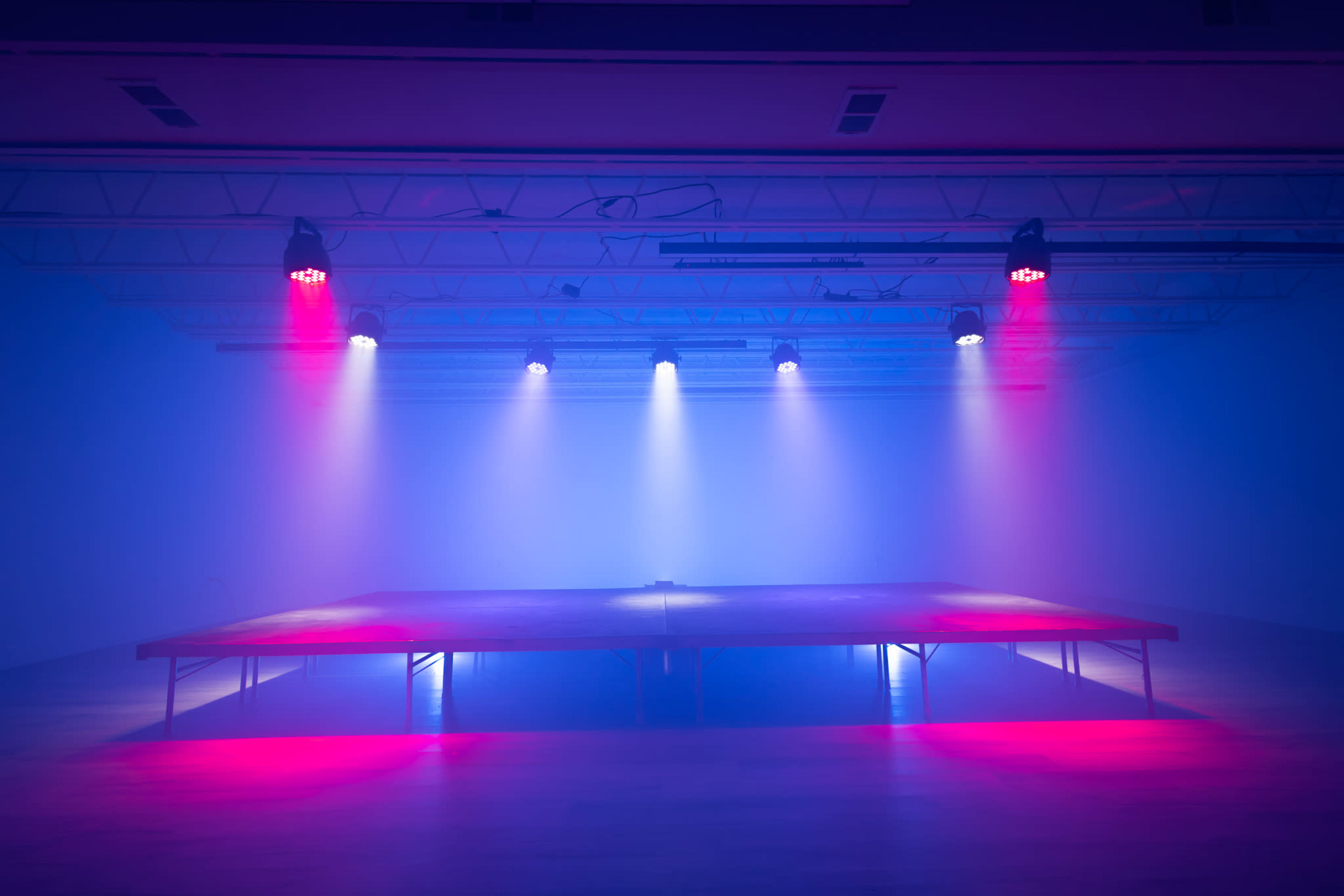 A stage is illuminated by various colored lights in a dimly lit room.