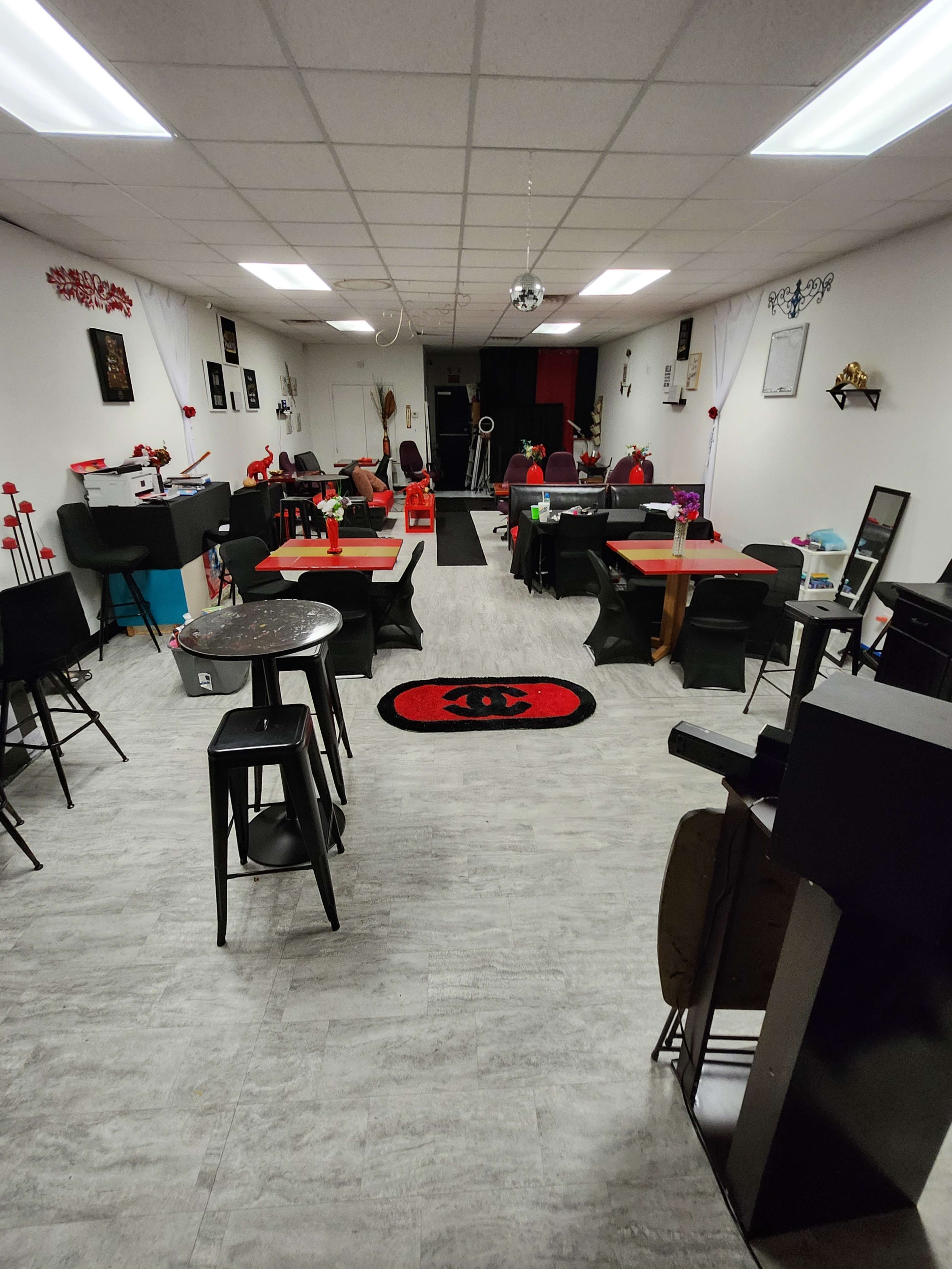 An indoor space set up with tables and chairs, decorated with red accents and a mirrored disco ball hanging from the ceiling.