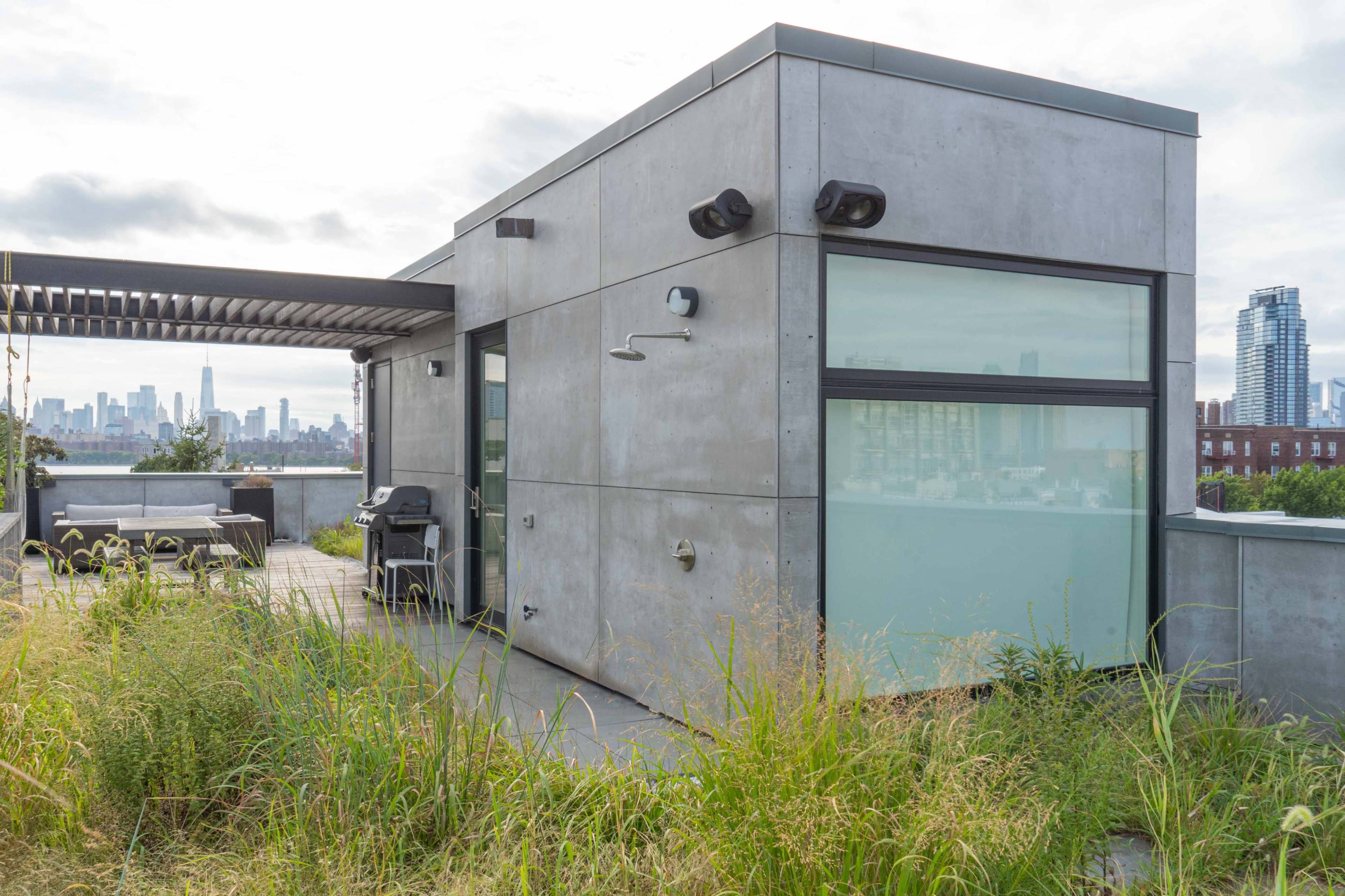 A modern concrete structure with large windows and outdoor amenities is set against a city skyline in the background.