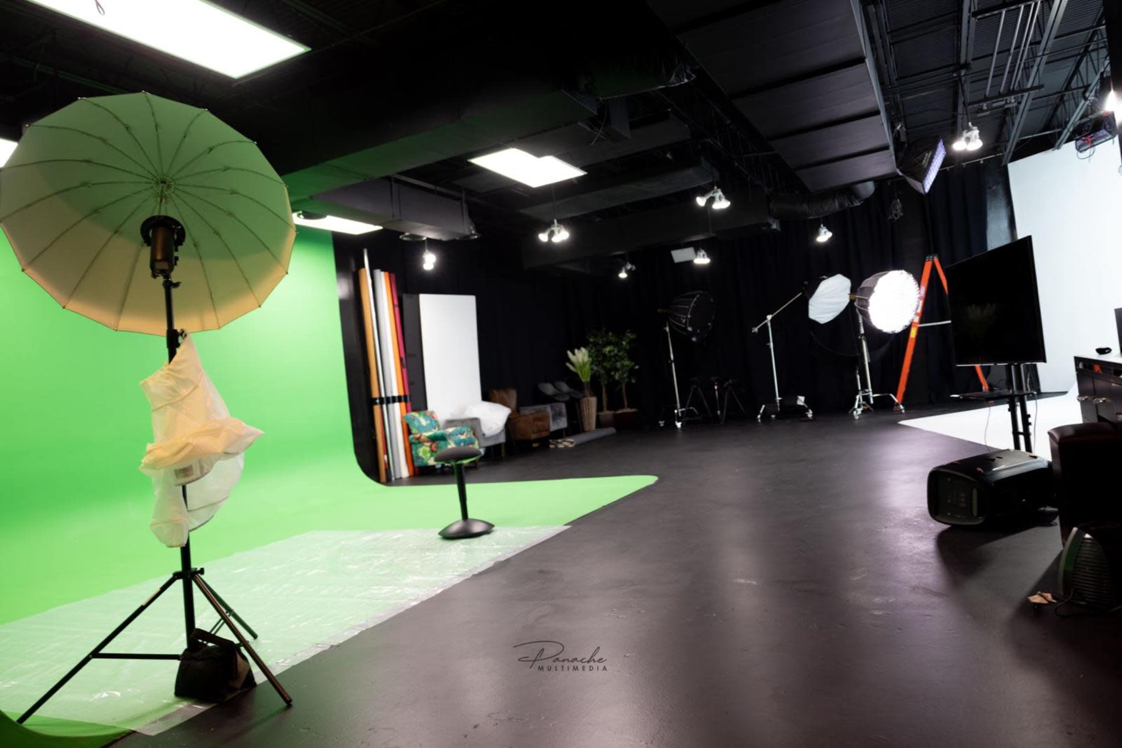 A photography studio equipped with green and white backdrops, lighting setups, and various props.