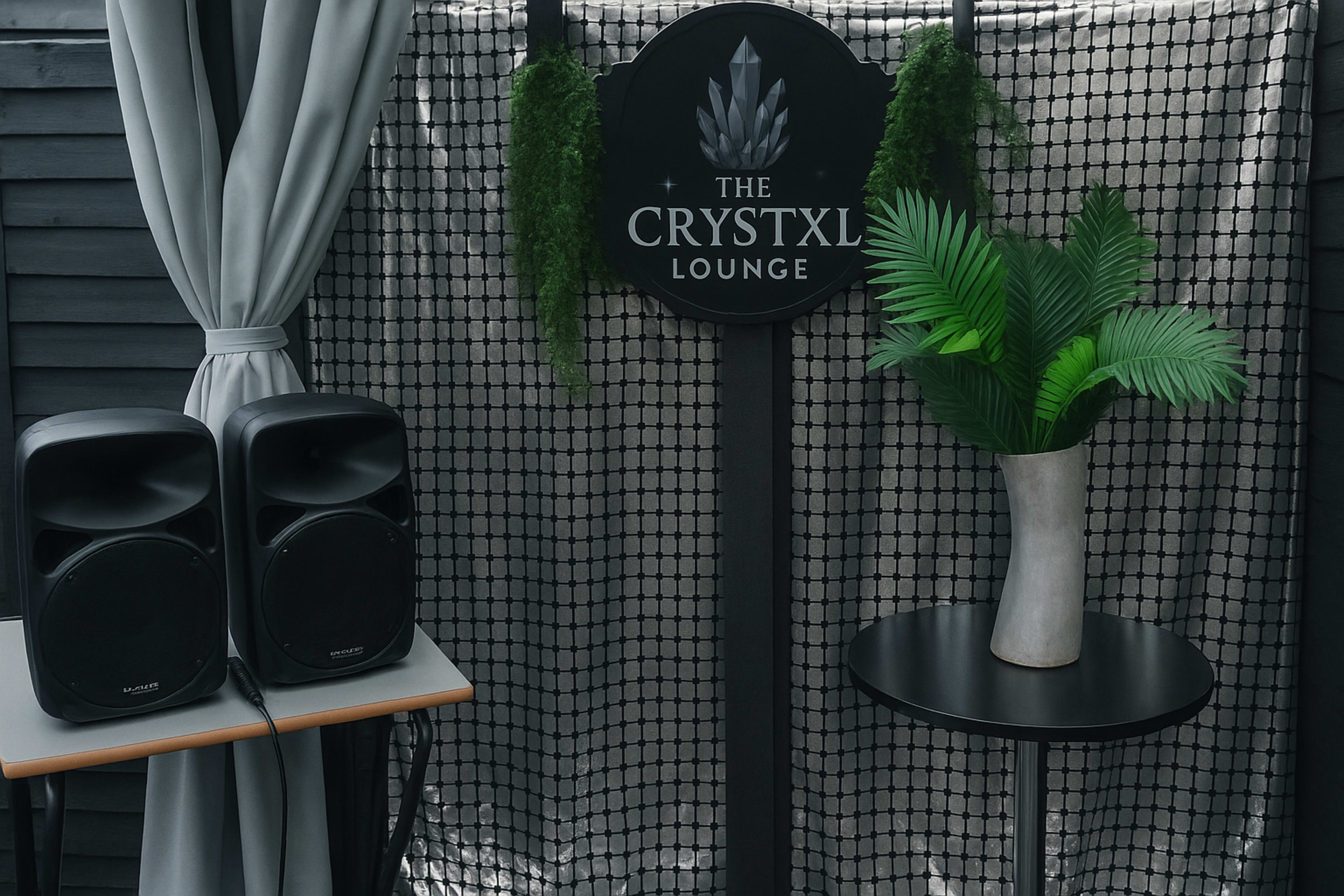 The image shows a decorative setup featuring two speakers, a black table, a potted plant, and a sign that reads "THE CRYSTXL LOUNGE" against a metallic backdrop.